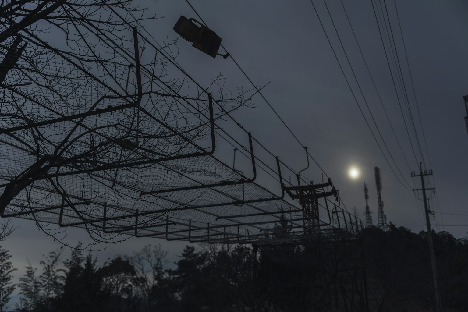 Une image montrant une nuit éclairée par la lune avec des lignes électriques de chemin de fer en silhouette