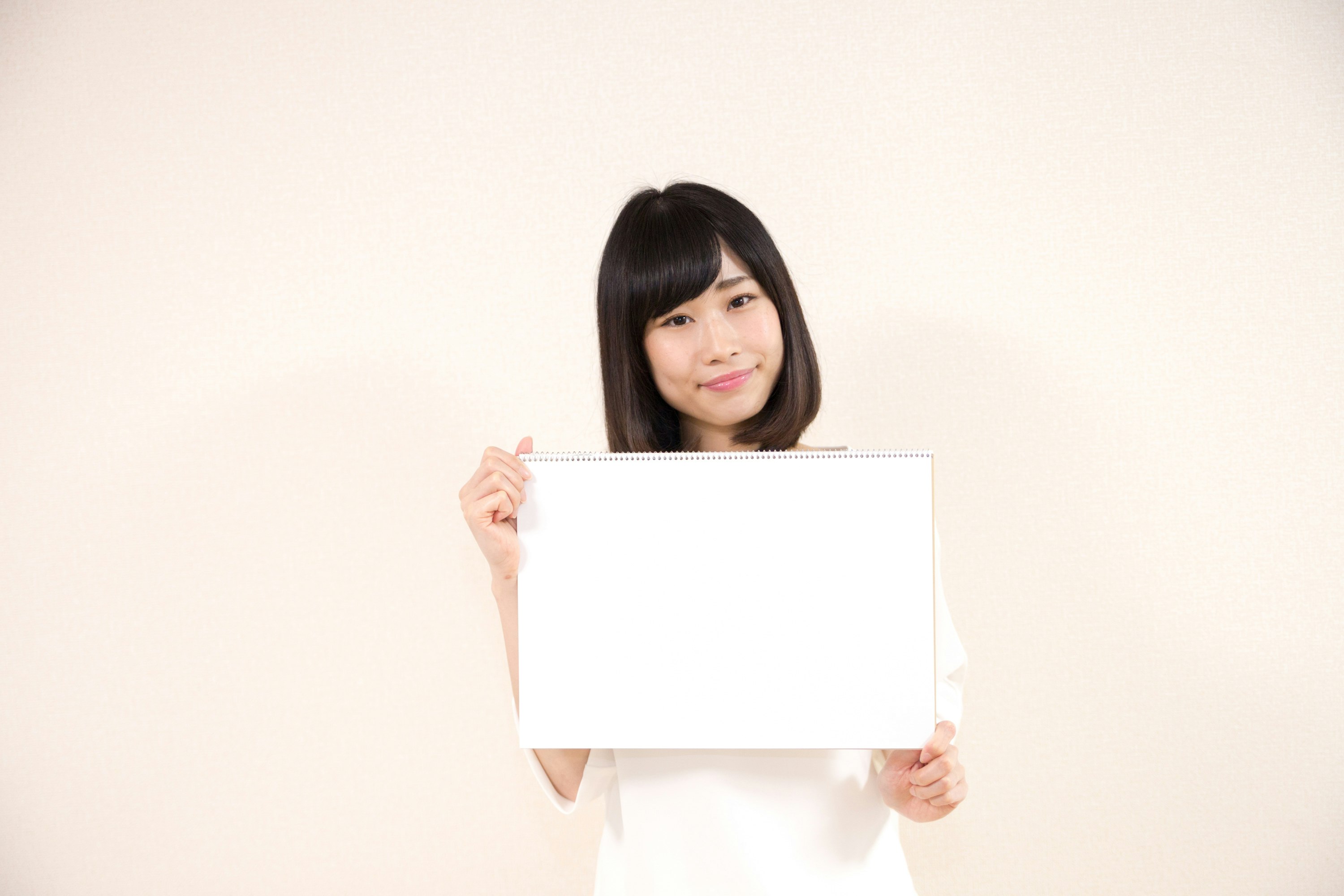Mujer sonriente sosteniendo un cartel en blanco sobre fondo blanco