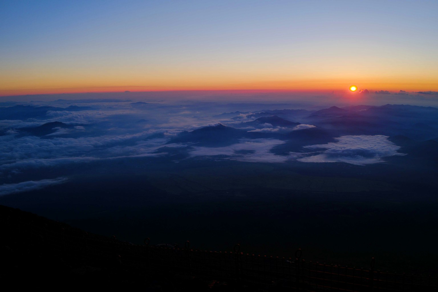 Wunderschöne Sonnenaufgangslandschaft mit Bergen über den Wolken und einem Verlauf von Blau zu Orange