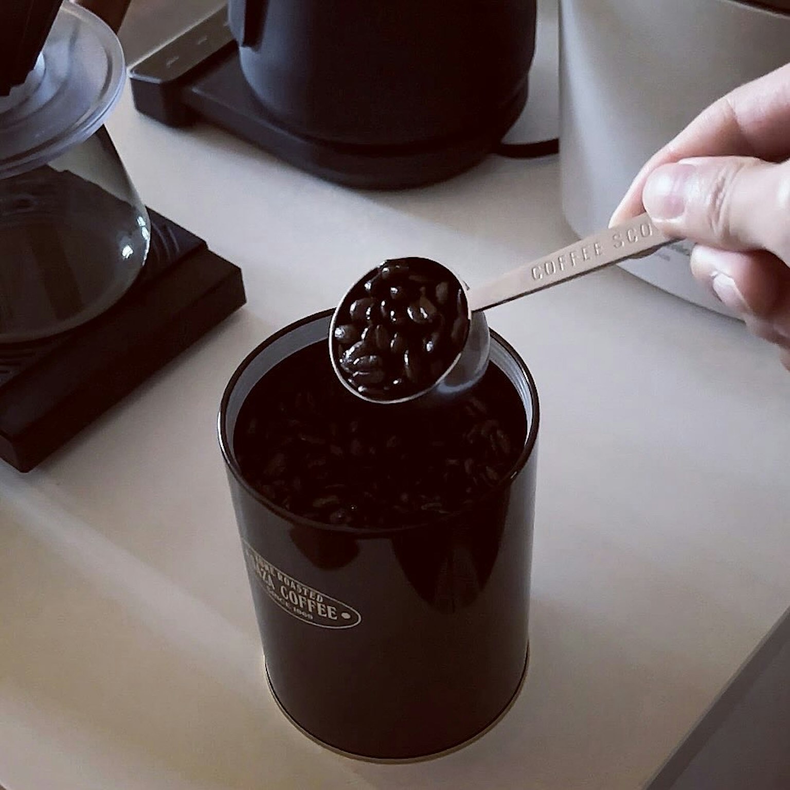 Cucharada de granos de café negros de un recipiente