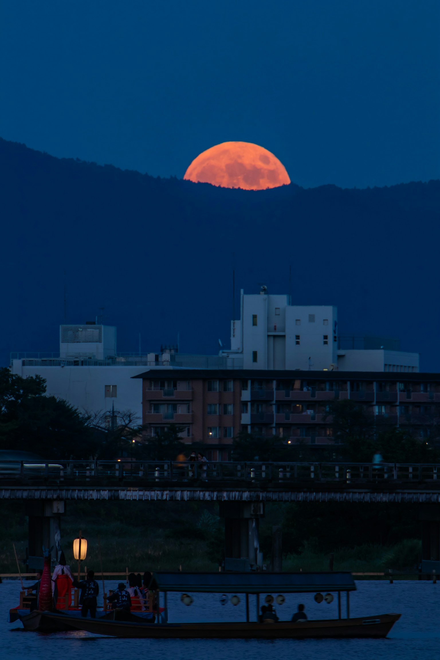 Bulan purnama besar terbit di atas pegunungan saat senja
