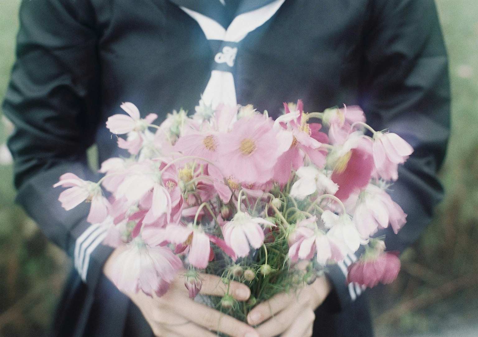 Personne en uniforme noir tenant un bouquet de fleurs roses