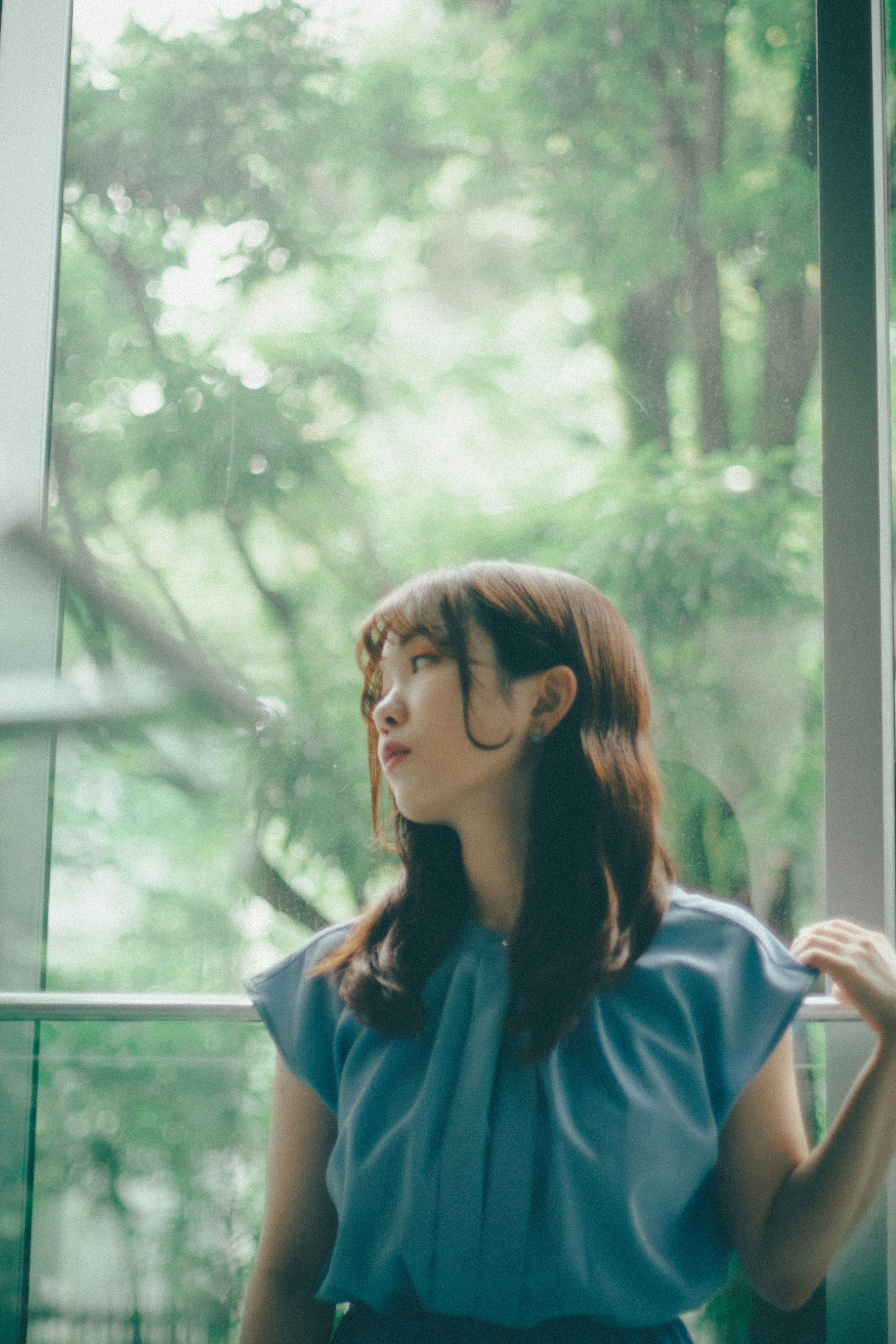 窓辺で微笑む女性と緑の背景