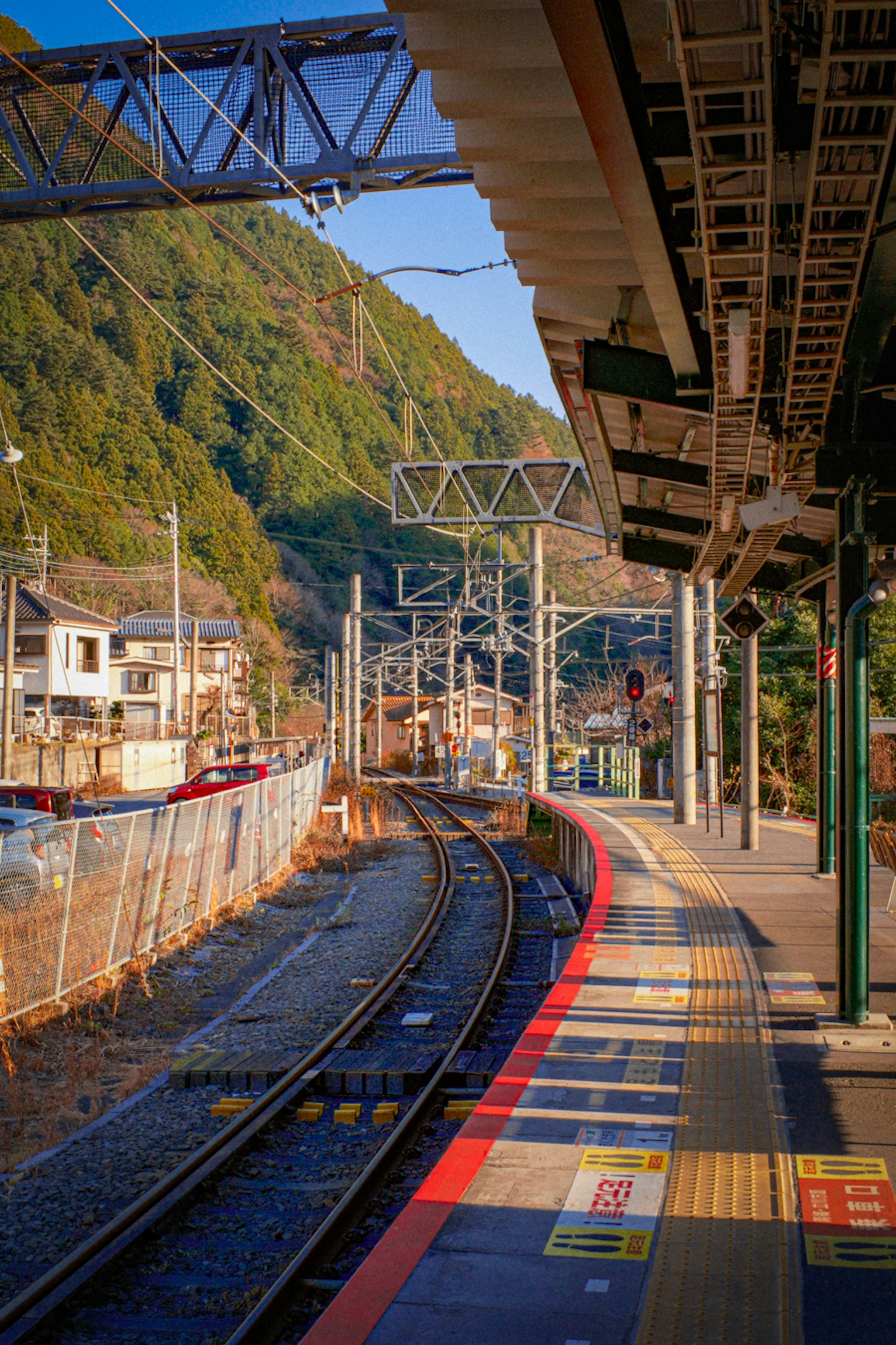 Piattaforma della stazione ferroviaria con binari curvi circondati da montagne
