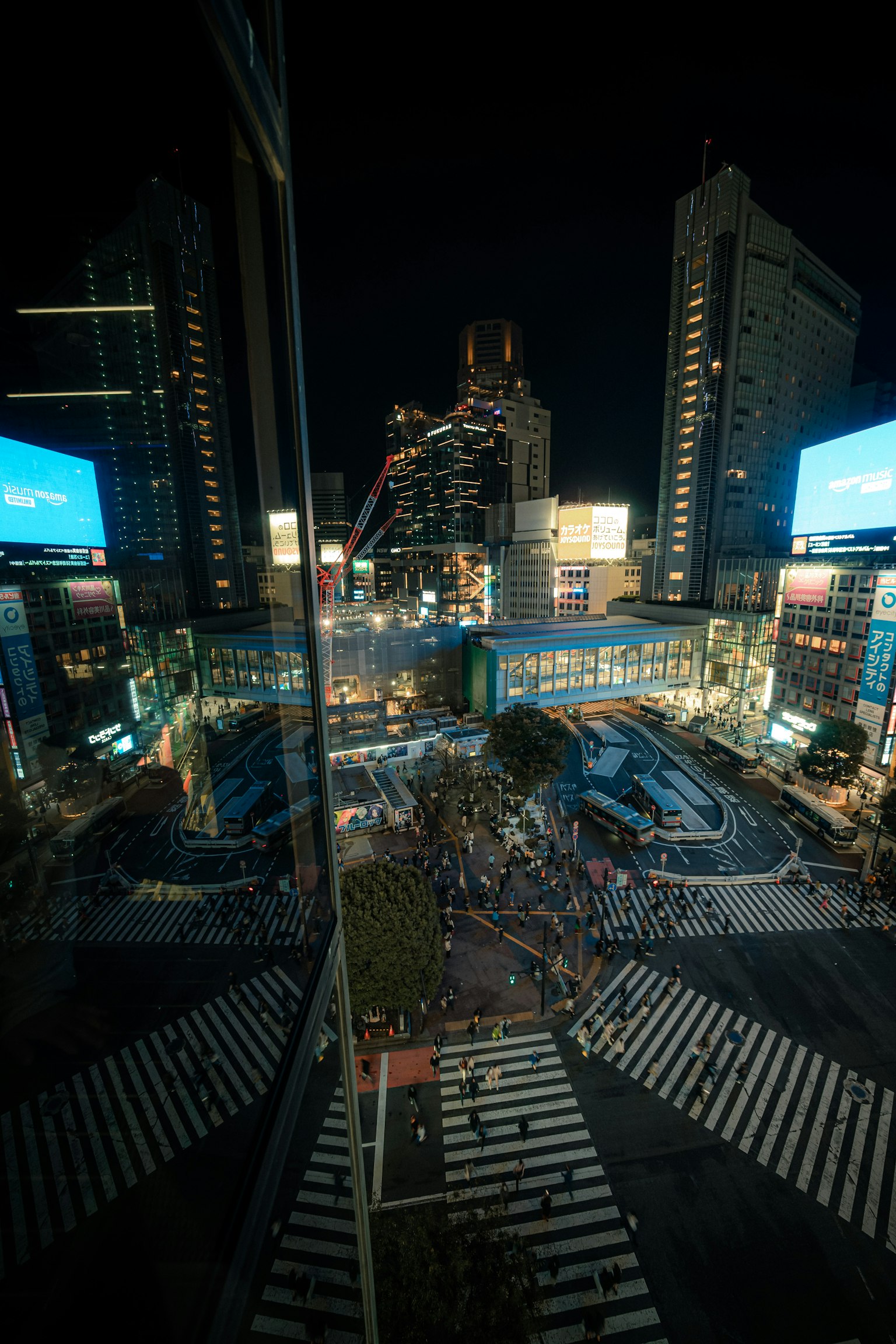Überblick über die Shibuya-Kreuzung bei Nacht mit Gebäuden und digitalen Bildschirmen