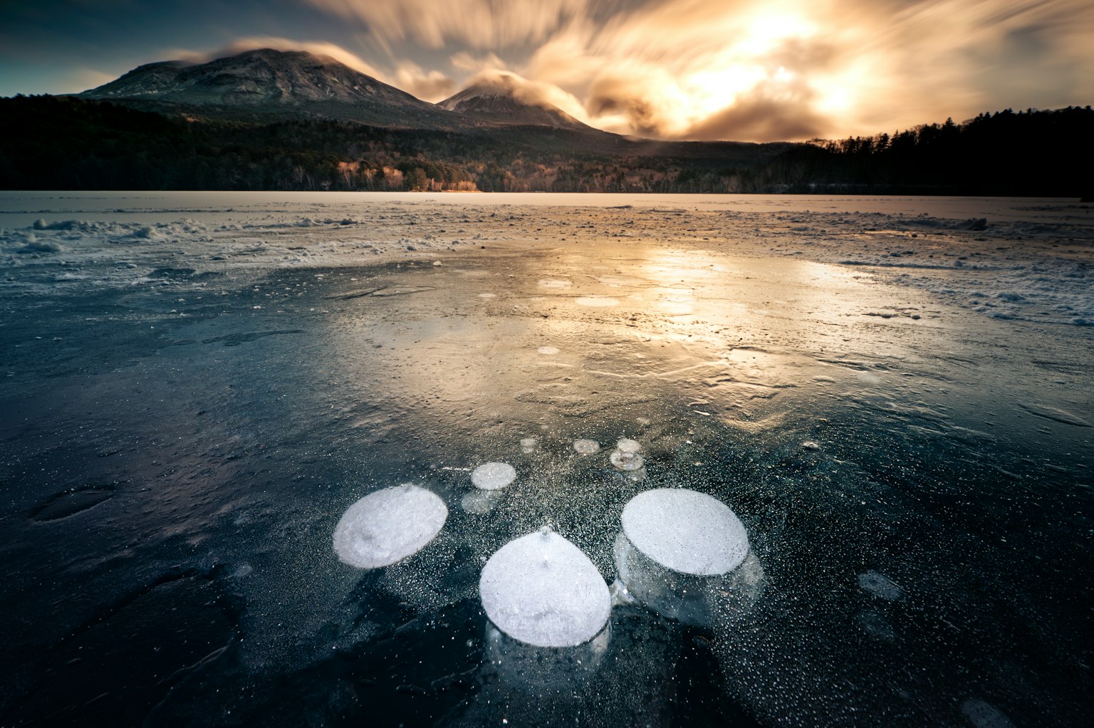Bulles piégées sous la glace avec un magnifique paysage montagneux