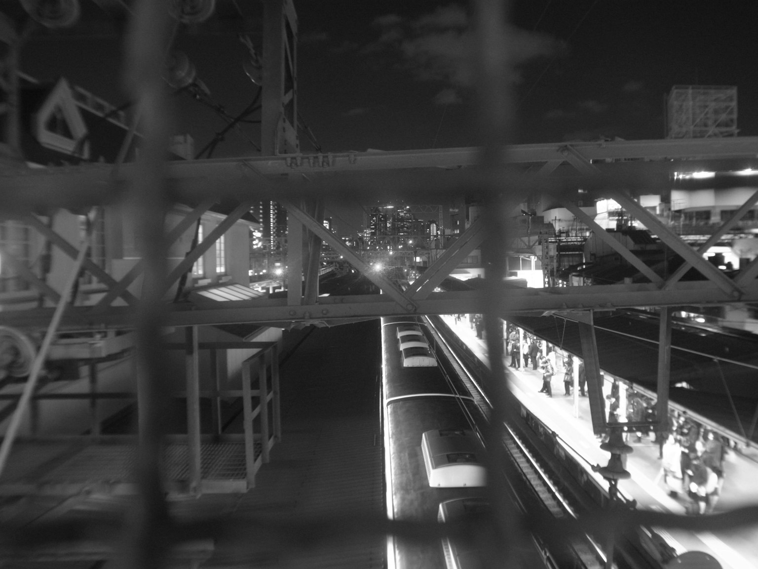 Paesaggio urbano notturno in bianco e nero con una stazione e un treno