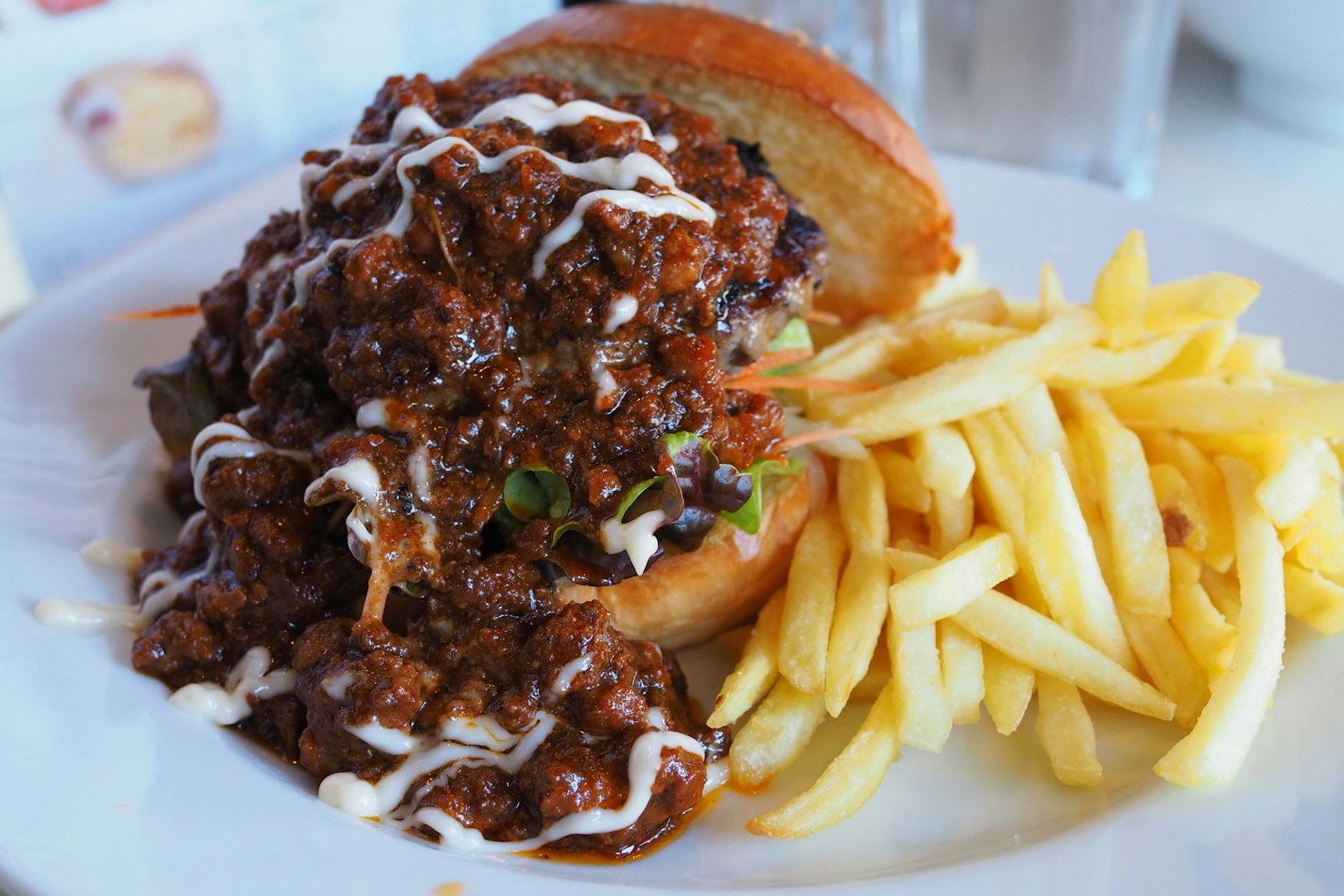A hearty burger topped with a rich meat sauce served with French fries