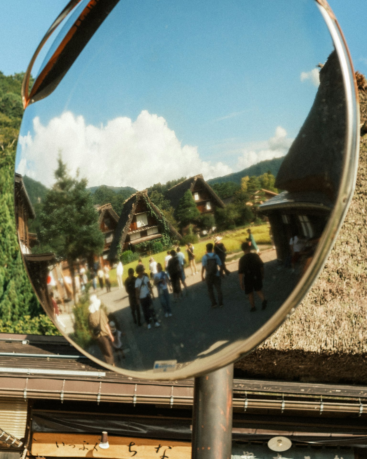 Riflessione di un paesaggio di villaggio e turisti in uno specchio convesso