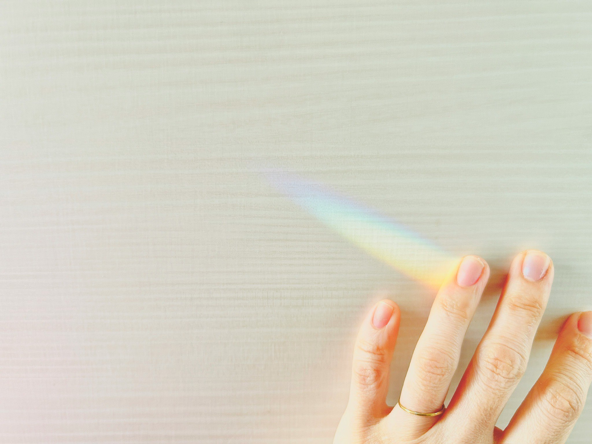close-up of a hand with a rainbow-tinted glow at the fingertips