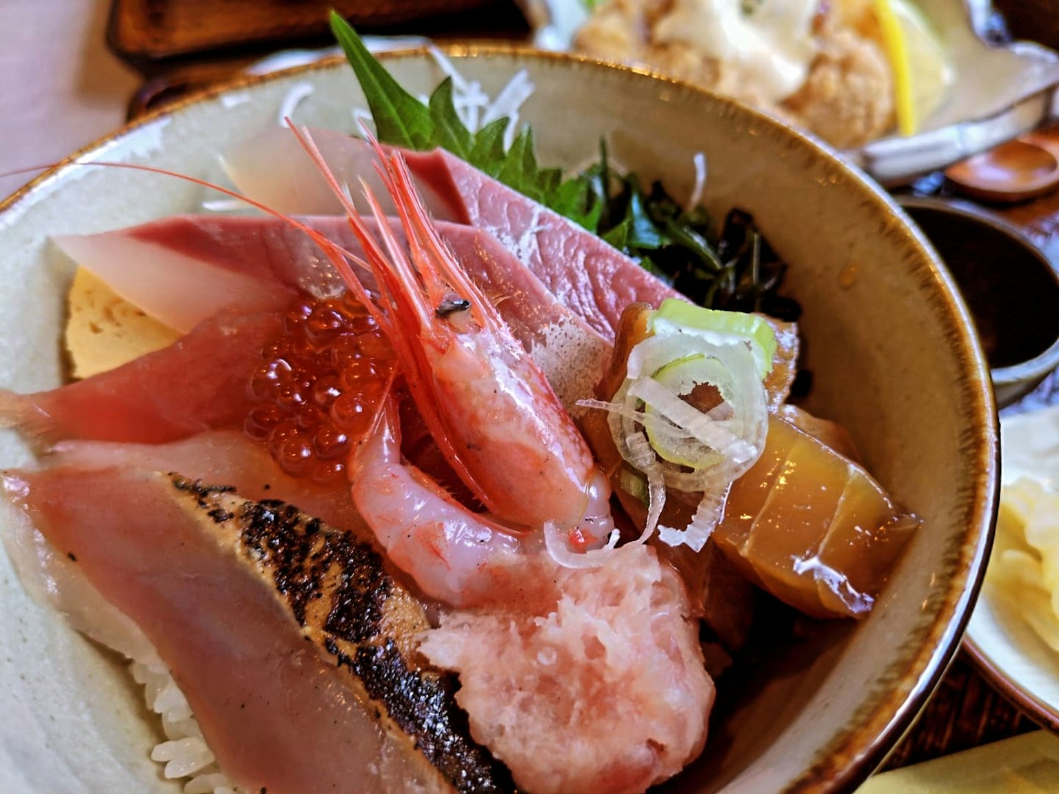 Imagen de un tazón de mariscos con sashimi fresco y arroz
