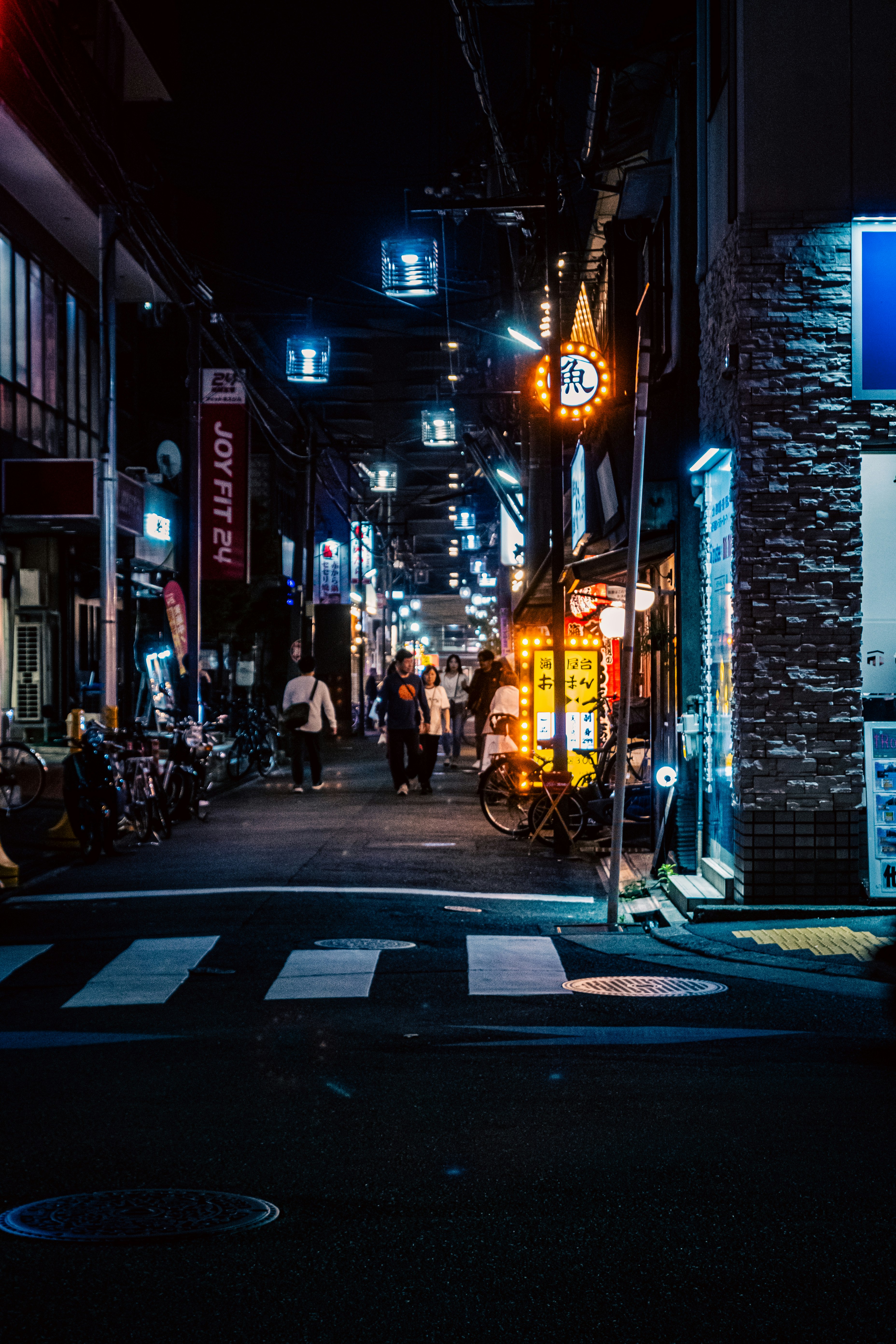 夜の路地に並ぶ看板と人通りのある商店街の街並み