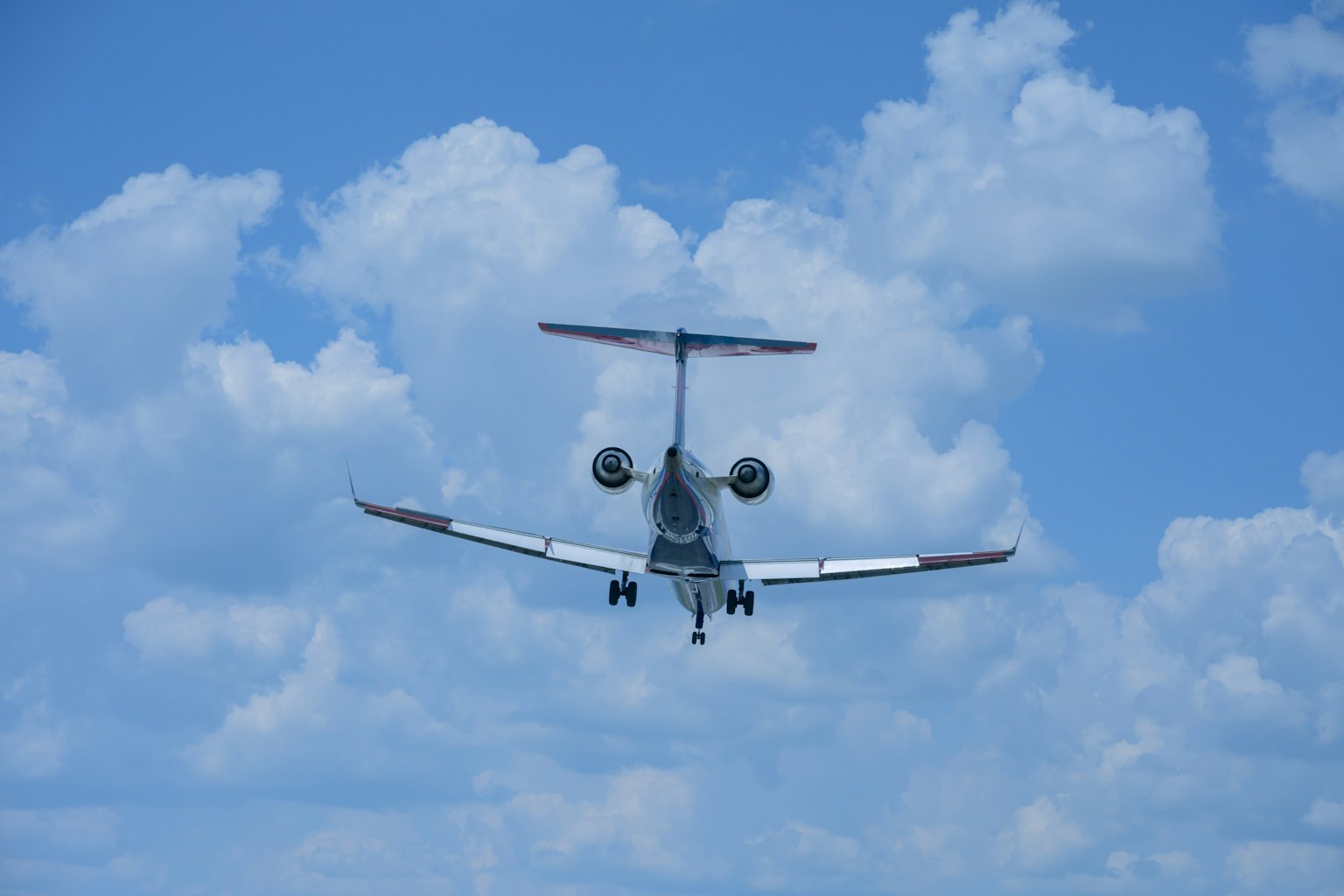 Rückansicht eines Flugzeugs, das in einem blauen Himmel mit weißen Wolken fliegt
