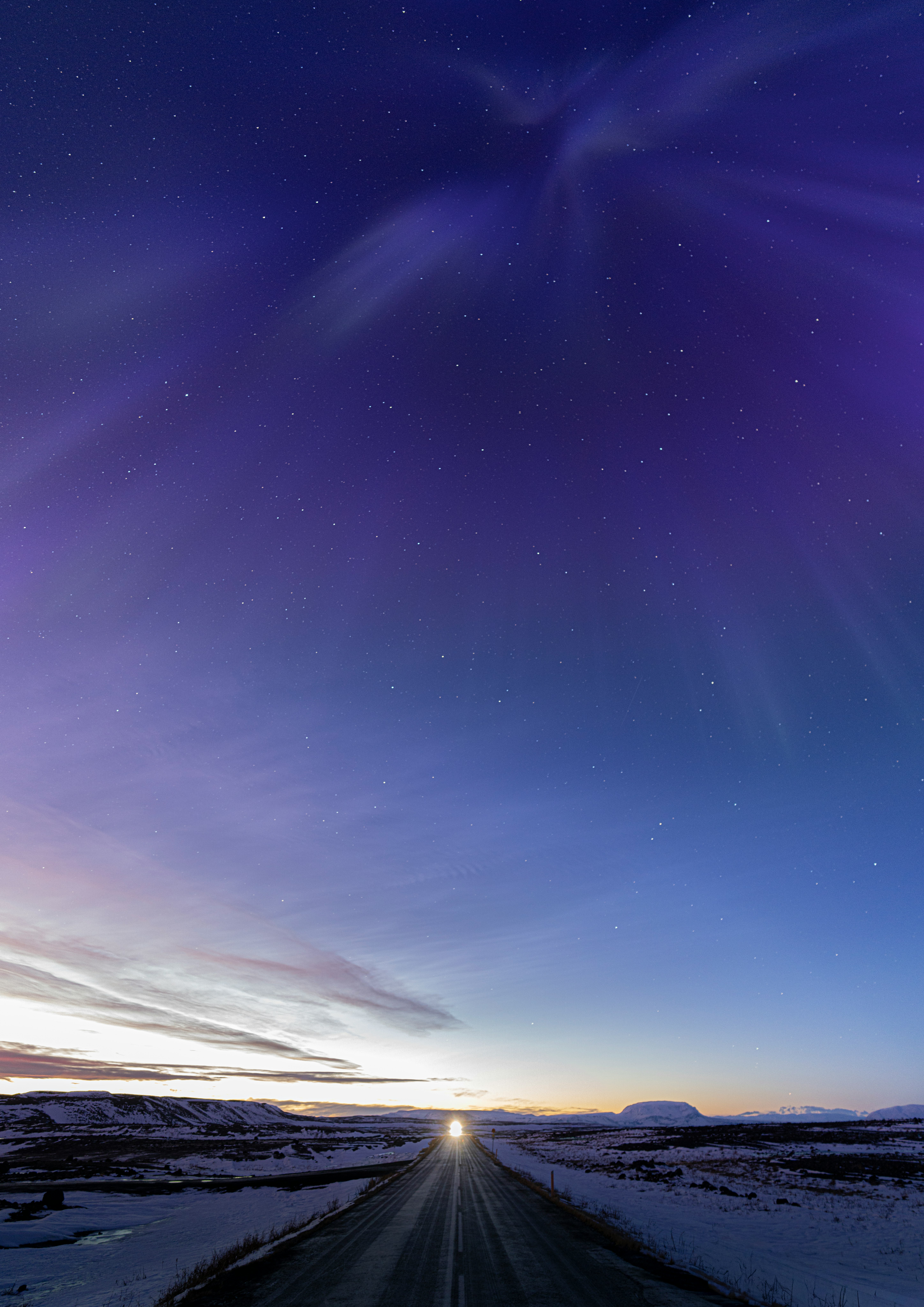 雪原の一本道を走る星空の下の夜景