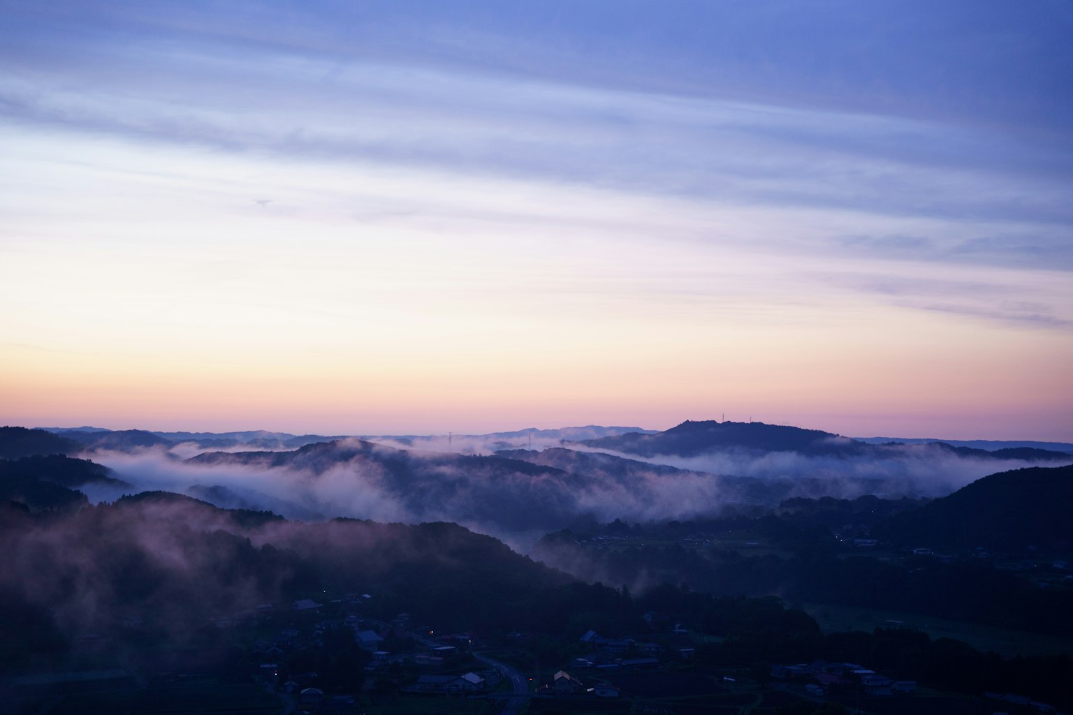 Paesaggio collinare avvolto nella nebbia con un bellissimo cielo al tramonto