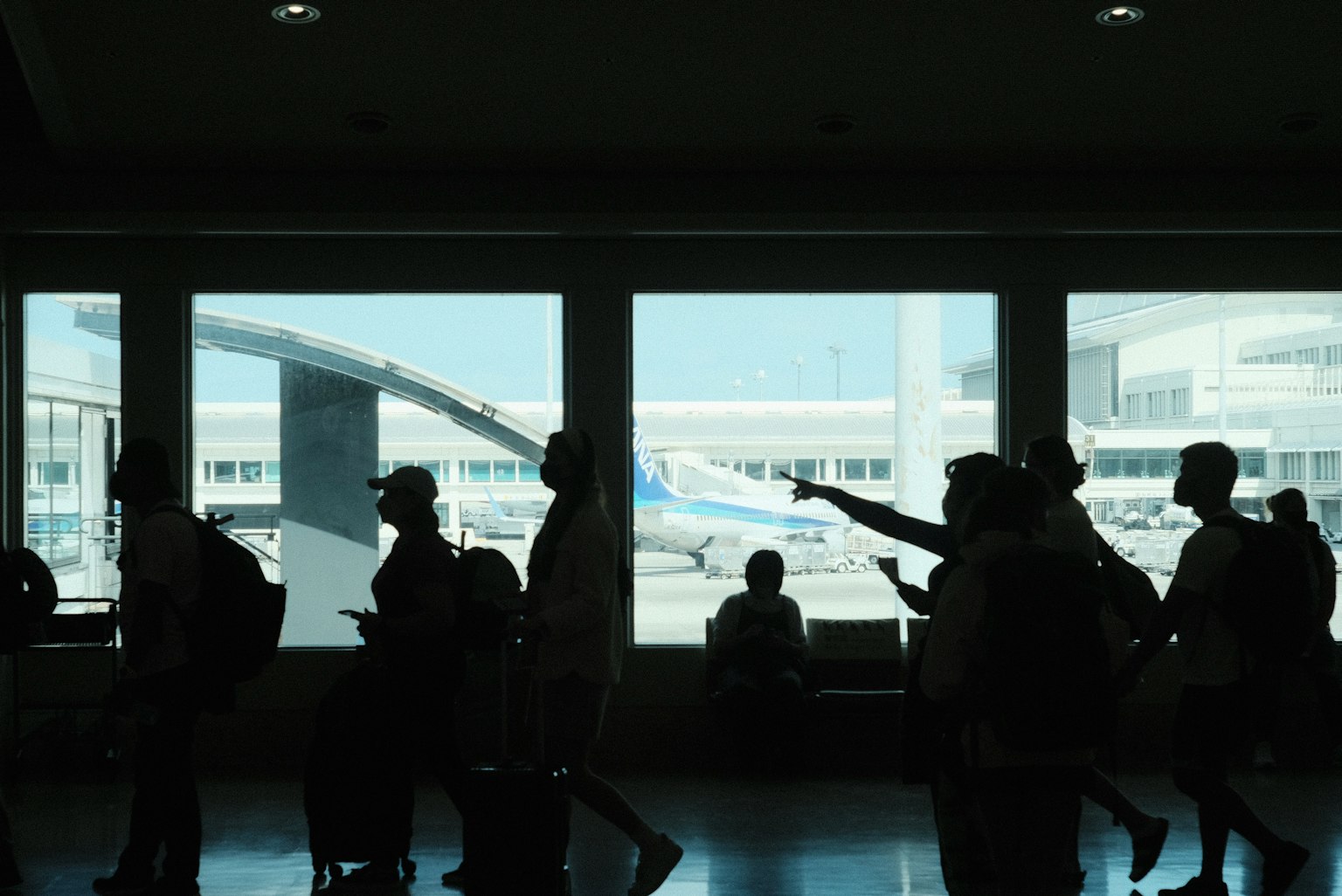 Silhouettes de personnes dans un terminal d'aéroport avec un avion visible