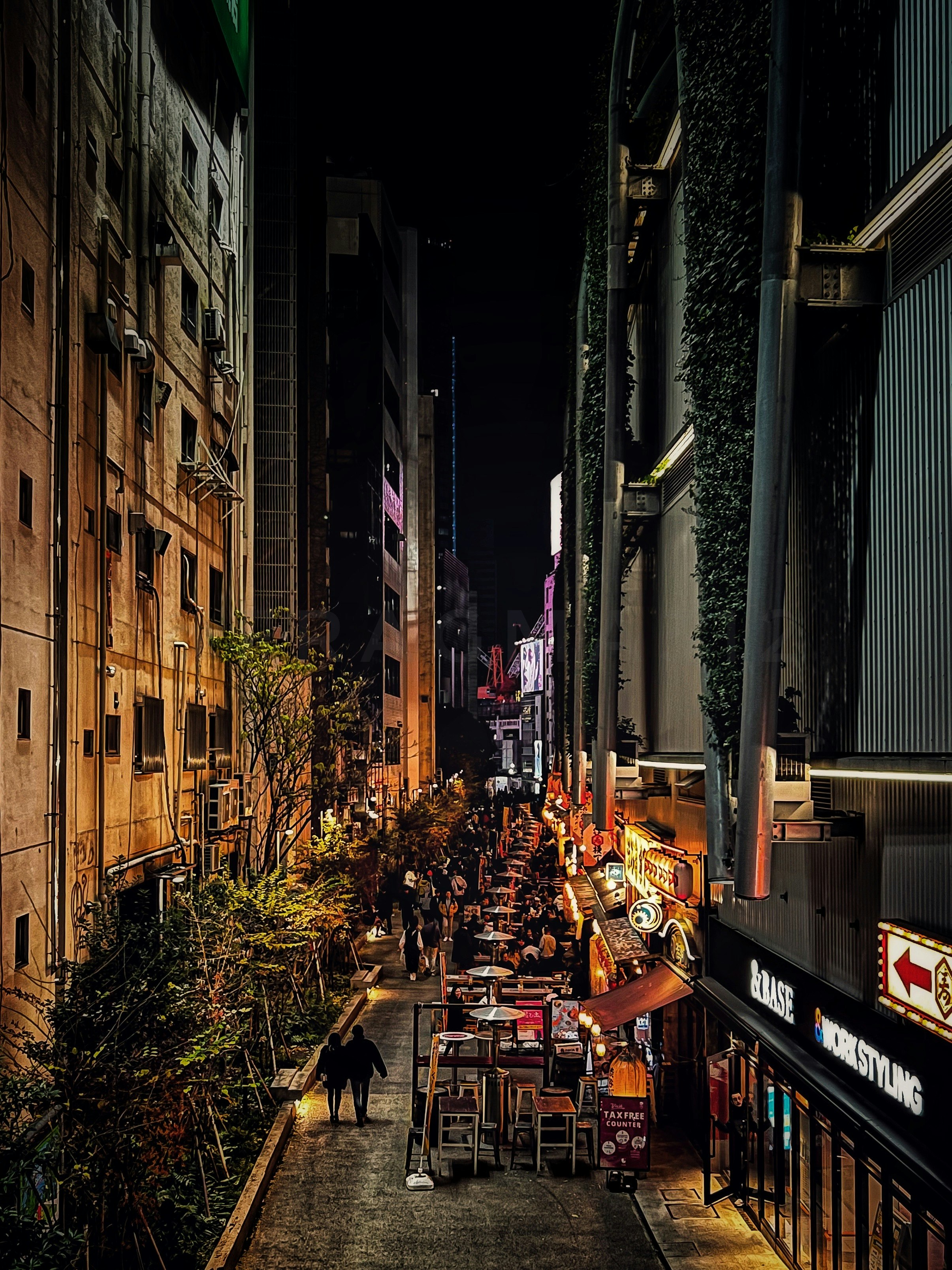 nighttime alley with street food stalls and signage