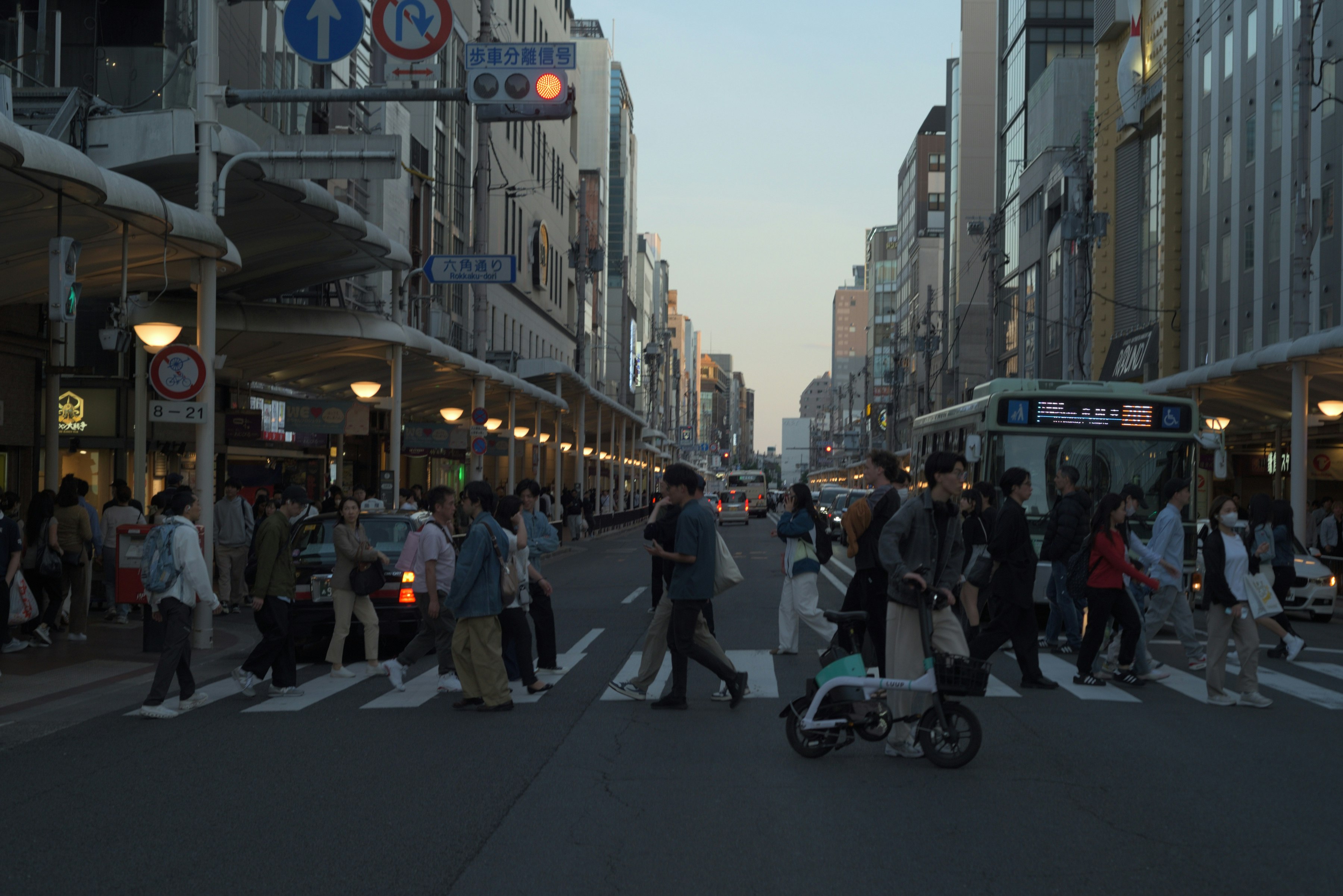夕暮れの街路で人と自転車が行き交う風景
