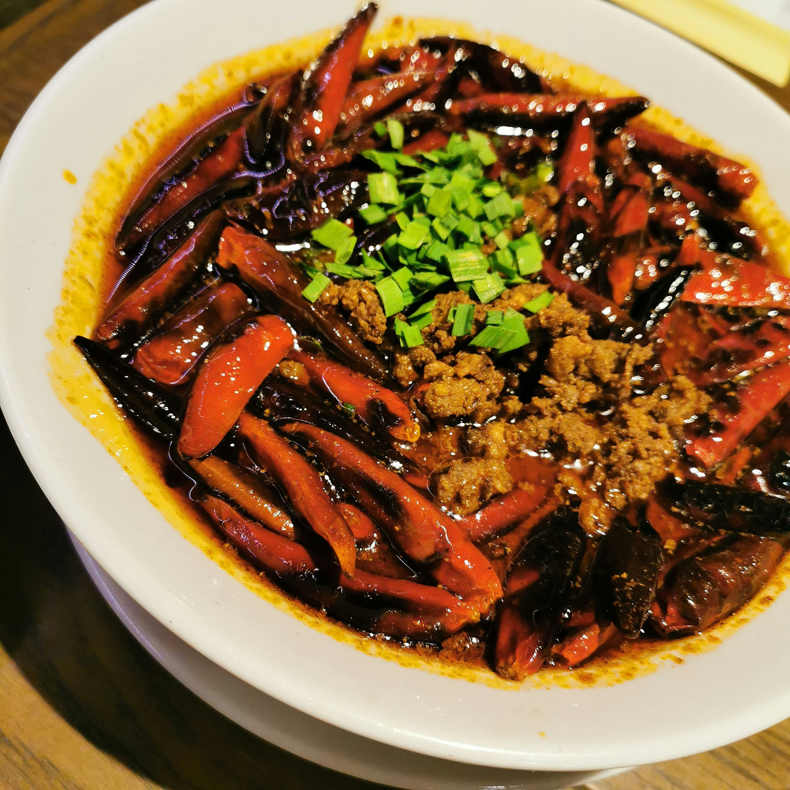 深色湯底上鋪蔥花的麵食