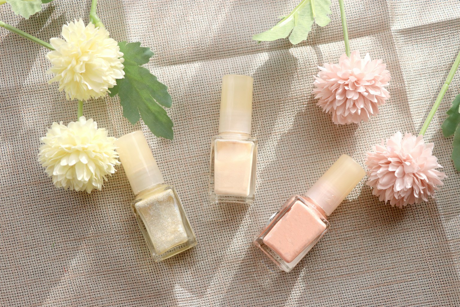 Nail polish berwarna lembut disusun dengan bunga dan daun halus dalam pengaturan yang indah
