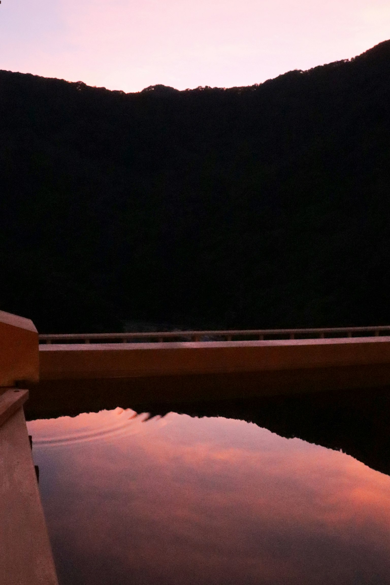 Reflection of sunset colors on water with mountain silhouette