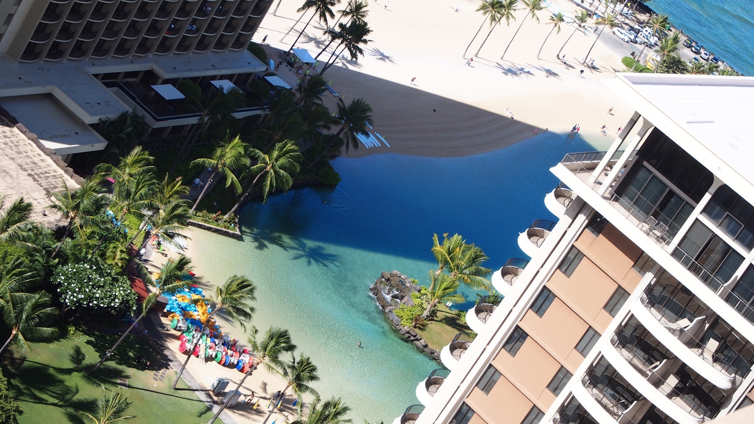 Vista aerea di una spiaggia e di una piscina con palme e sdraio colorate