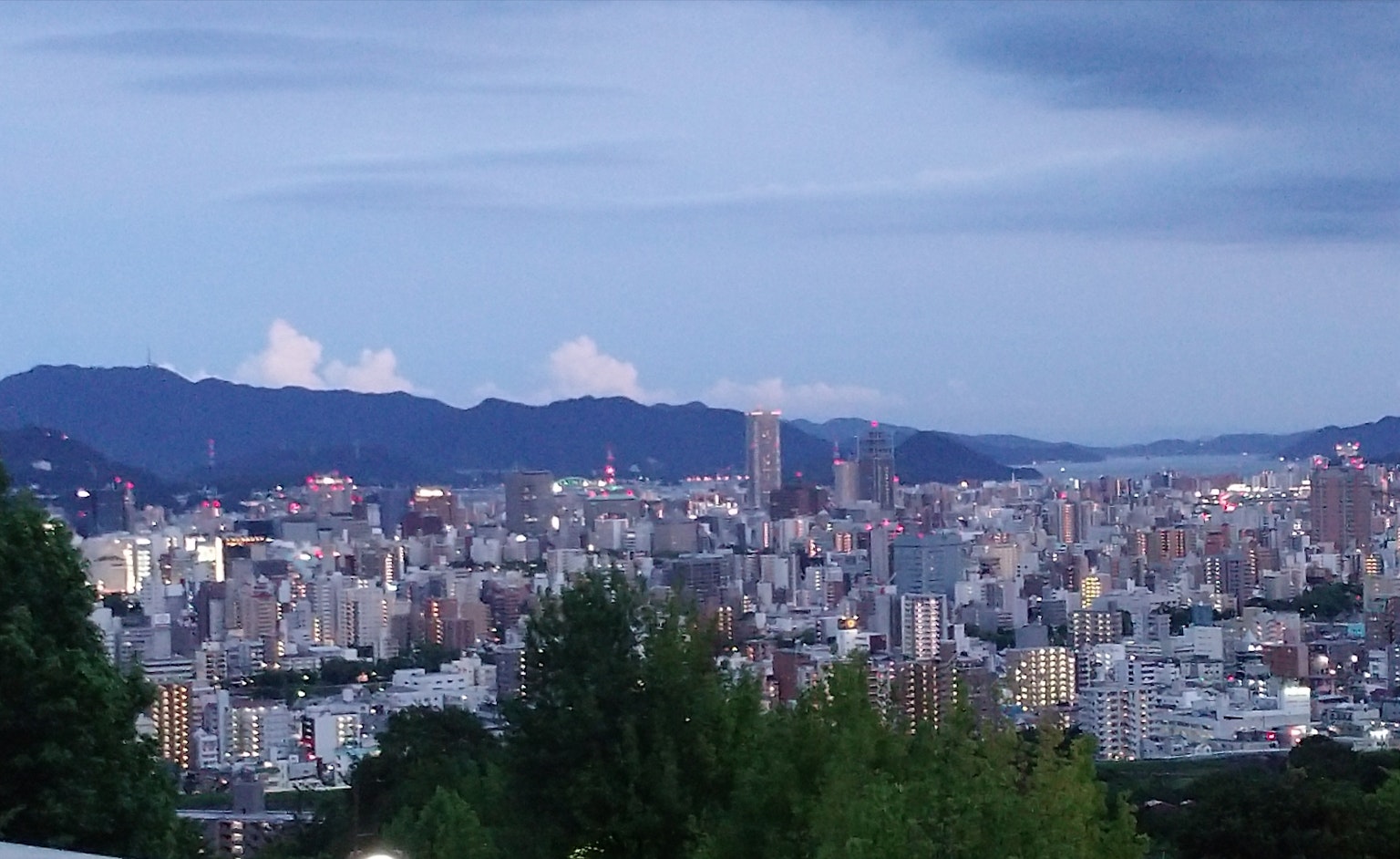 Cityscape under a blue sky with mountains in the background