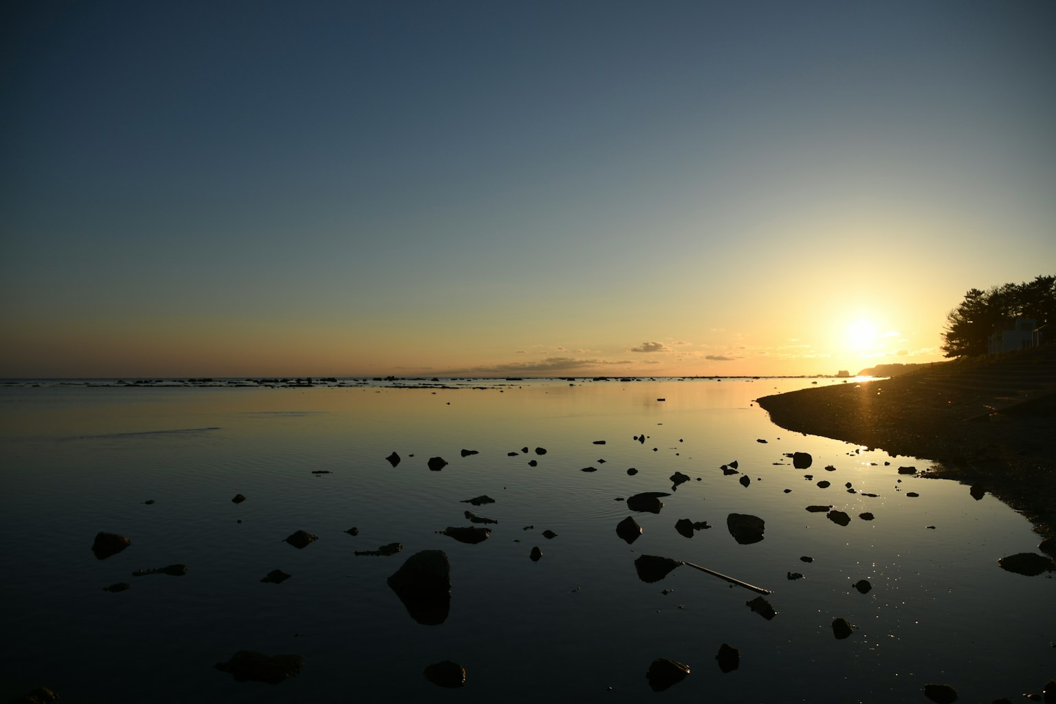 Serene seascape at sunset with scattered rocks along the shore