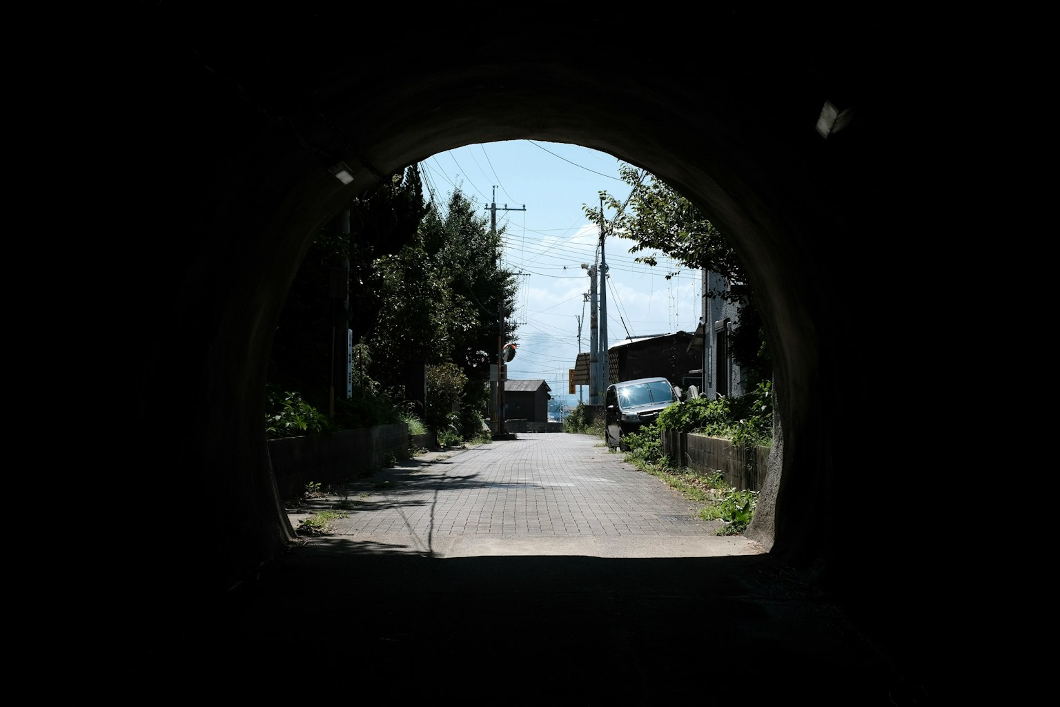 Blick auf eine helle Straße und blauen Himmel durch einen Tunnel