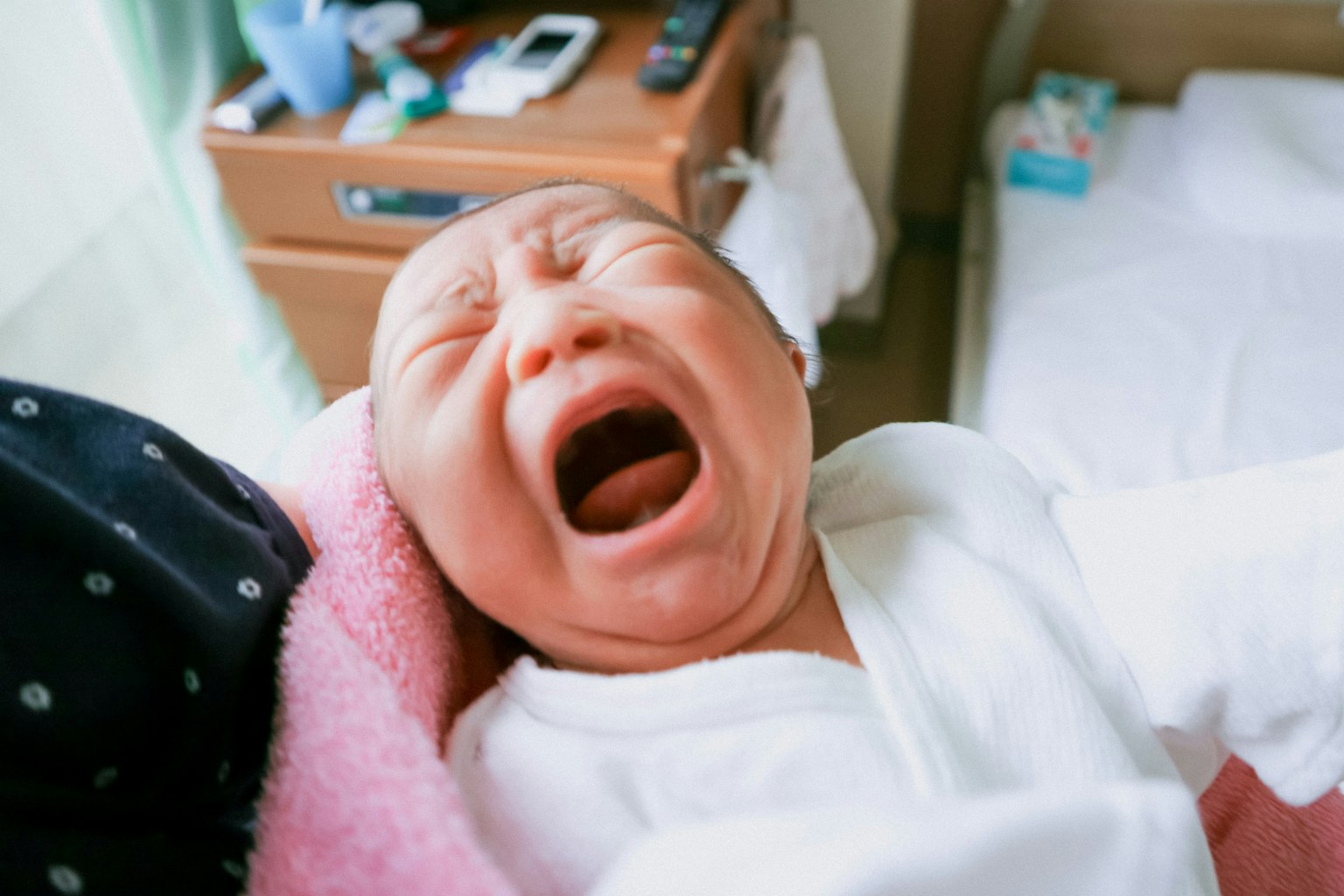 Image of a crying newborn baby in a hospital setting
