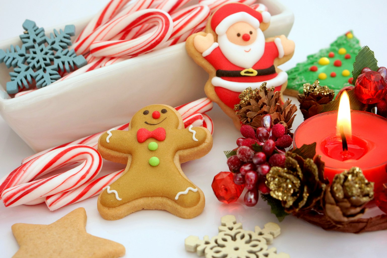 Pengaturan meriah dengan kue Santa Claus pria jahe tongkat permen lilin merah dan kerucut pinus di atas meja