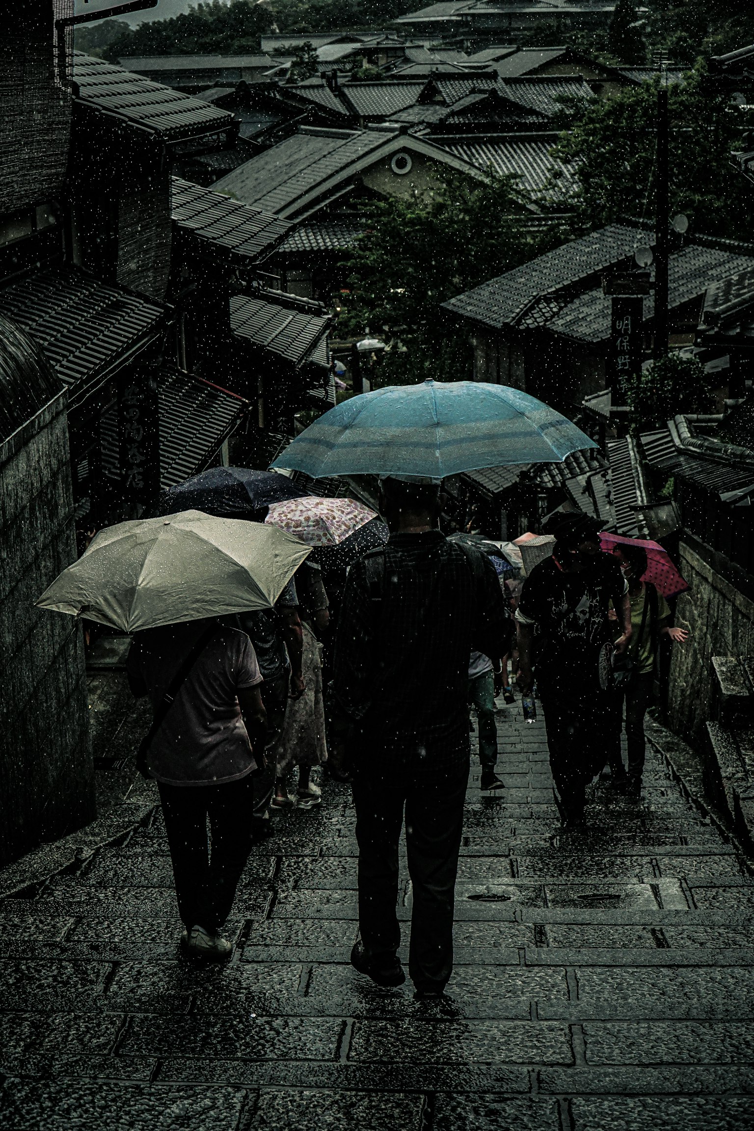 人们在雨中撑着伞走在石阶上