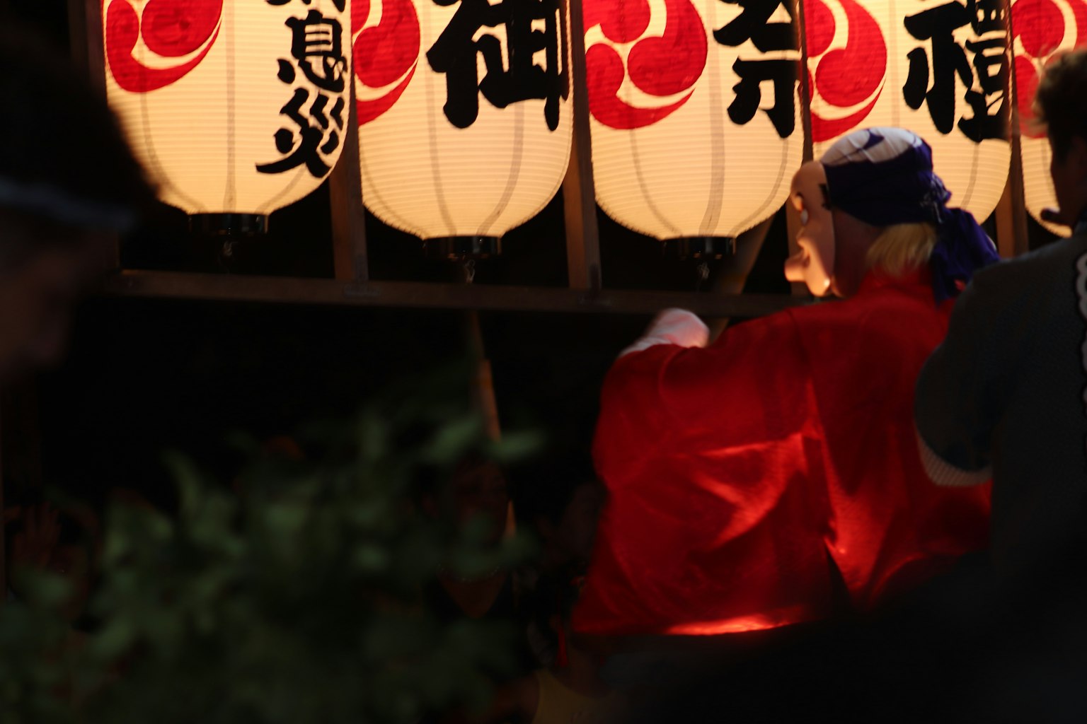 身穿紅色服裝的人站在夜間節日的白色燈籠前