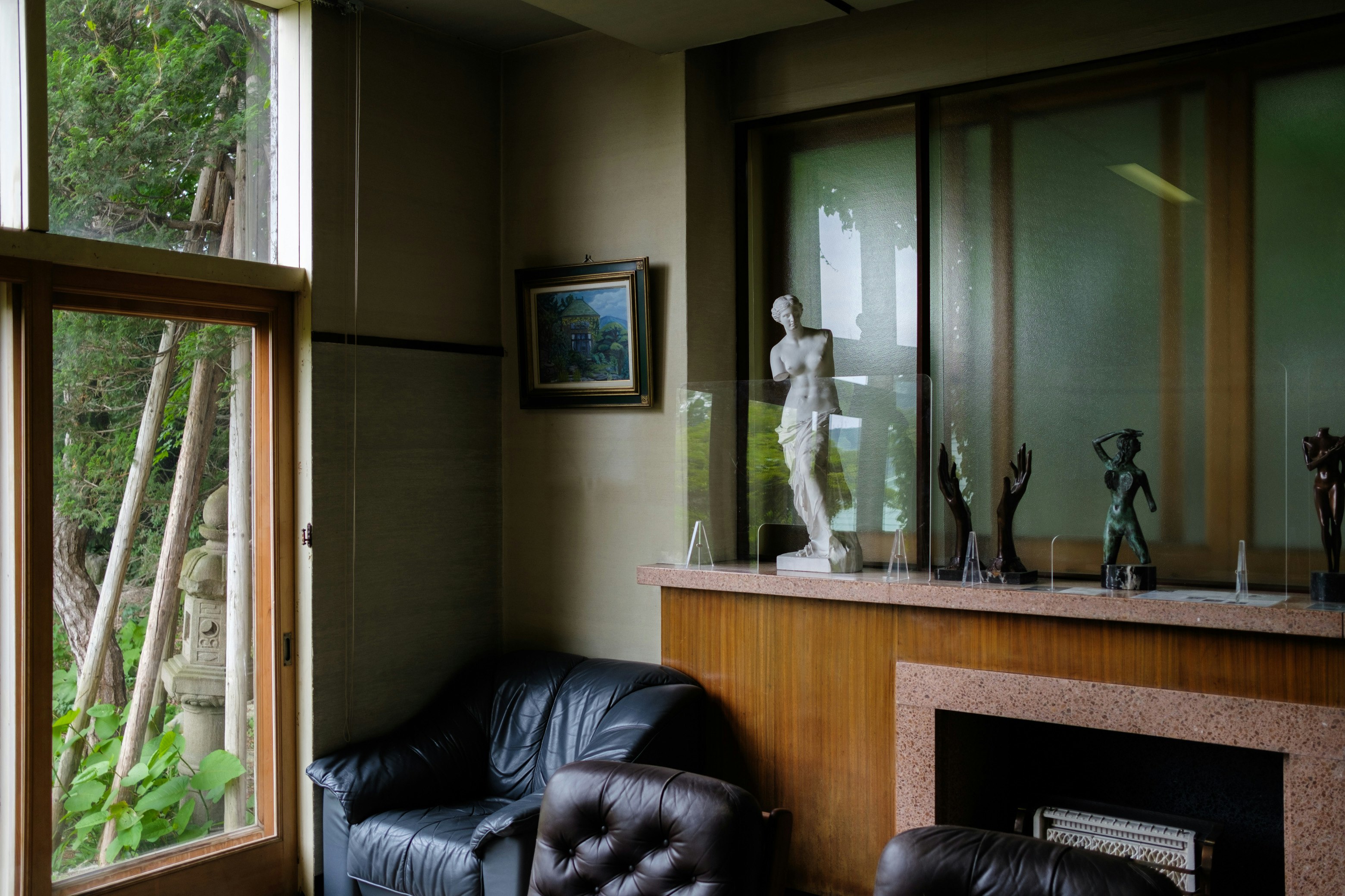 Indoor living room scene with sofa, fireplace, and decorative figurines by a large window