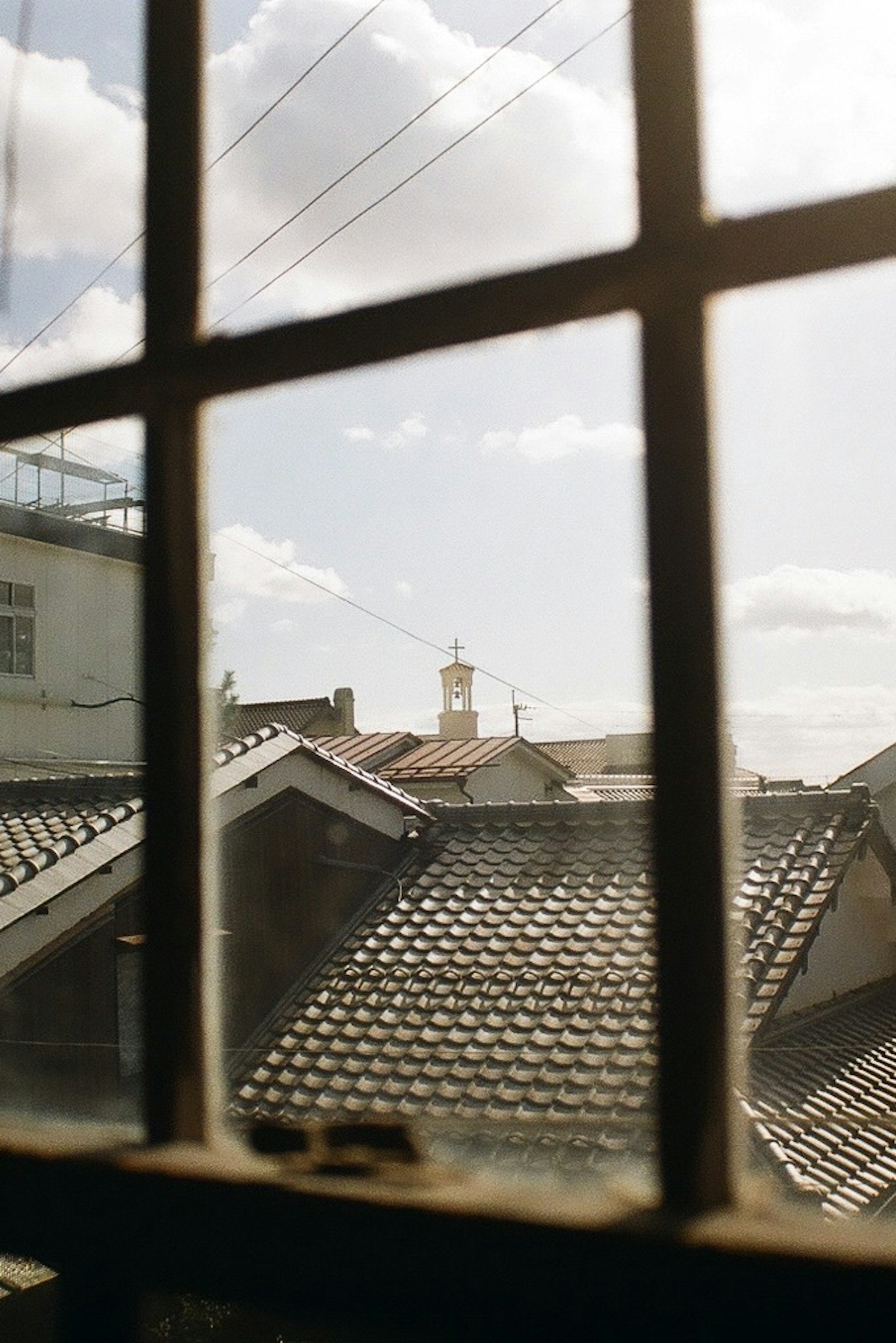 Vista attraverso una finestra che mostra tetti e un campanile