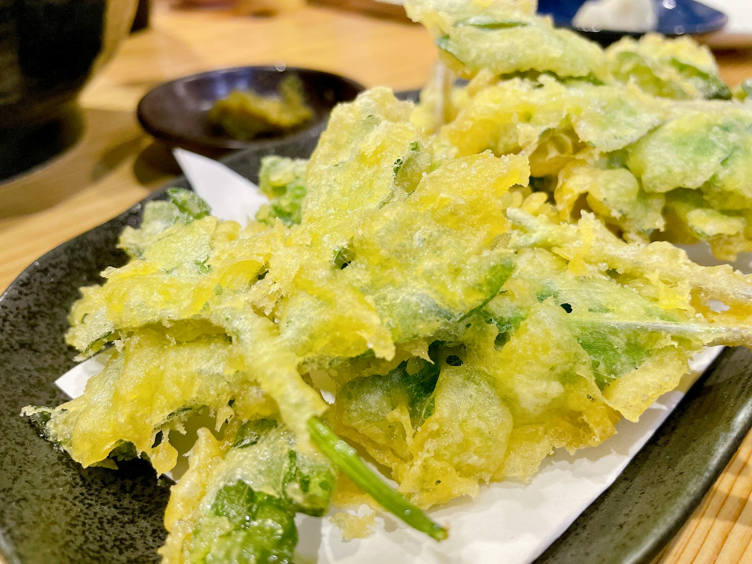 Une assiette de tempura assorti avec une pâte croustillante jaune et des légumes verts