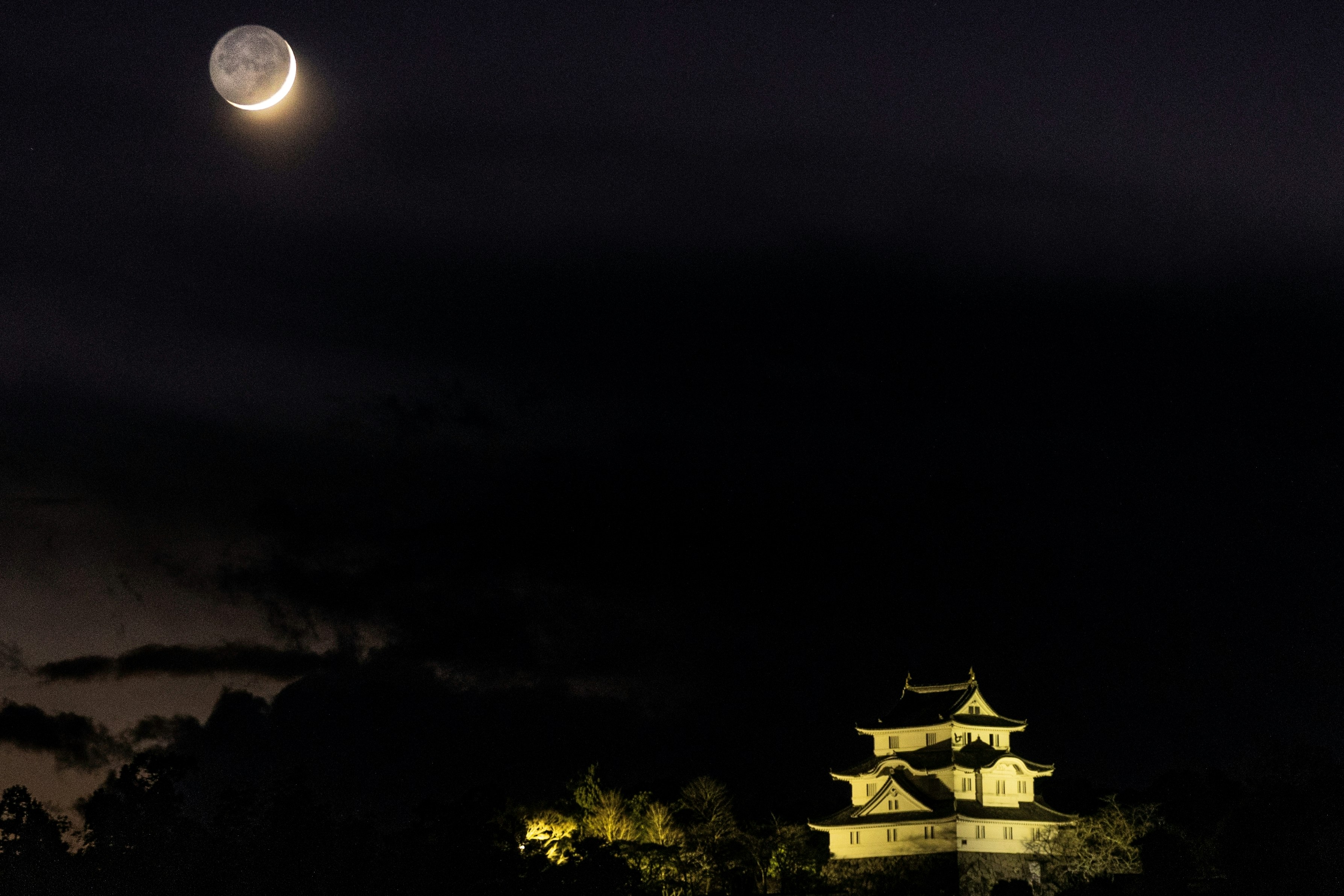 夜空の下、ライトアップされた城と雲のシルエット