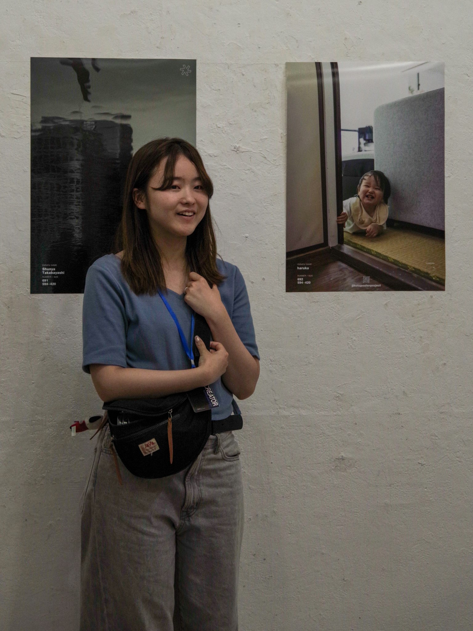 Une femme se tenant devant des photos accrochées au mur souriante en tenue décontractée