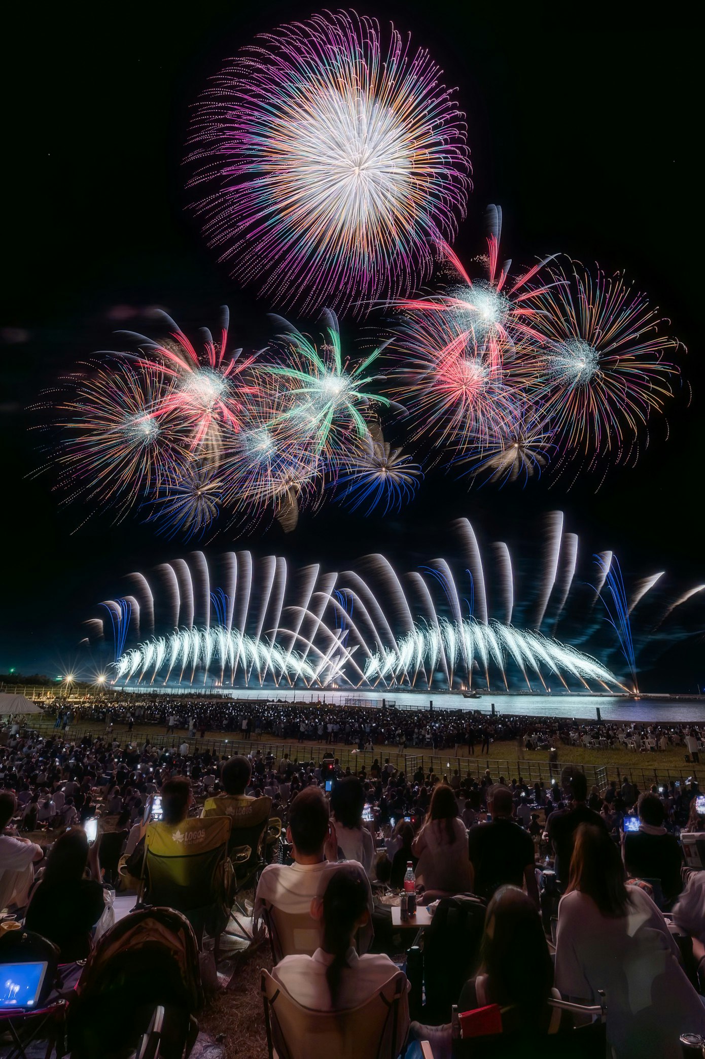 夜空に咲く花火と観客席の大勢の人々