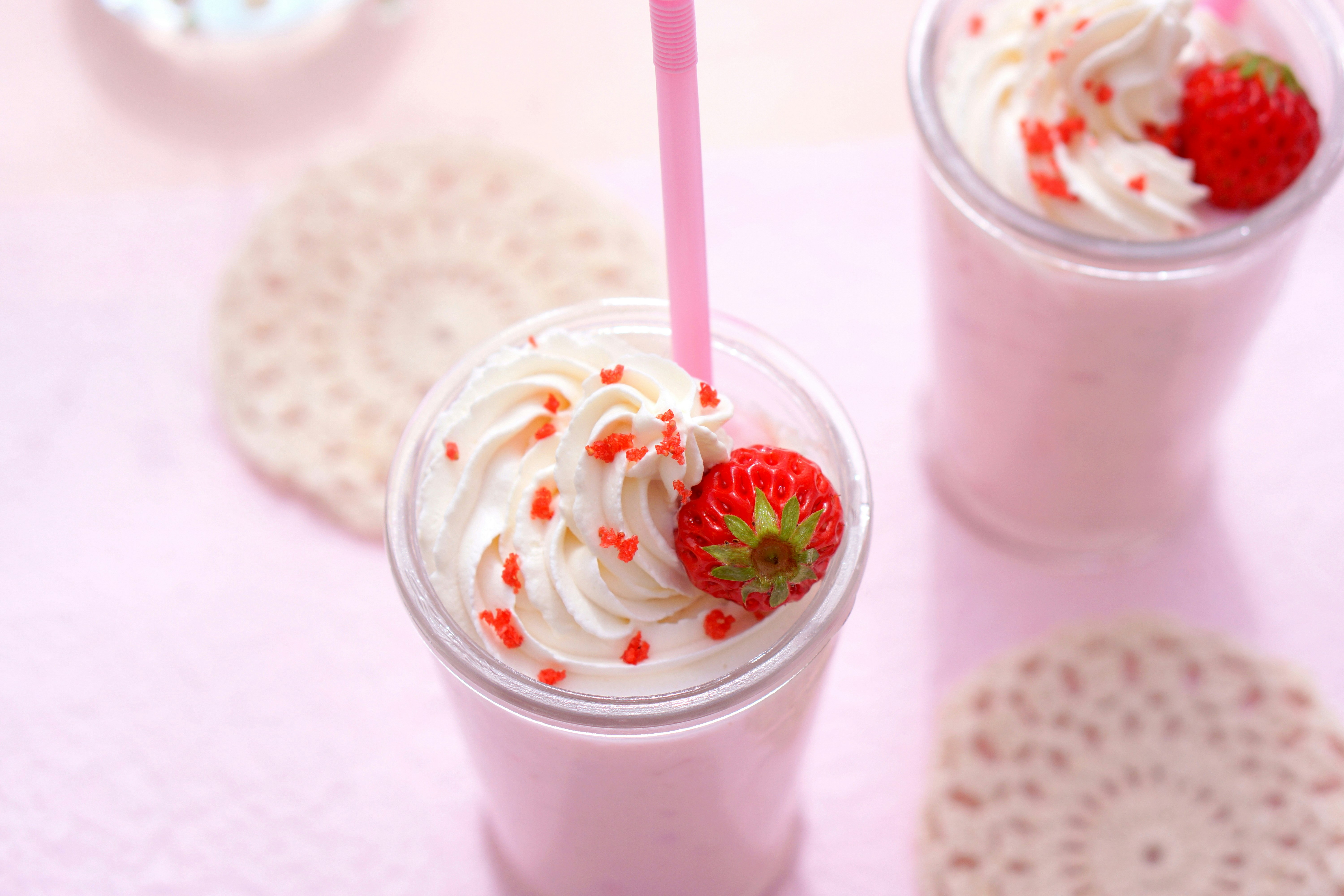minuman whipped stroberi dengan sedotan di meja bergaya kafe