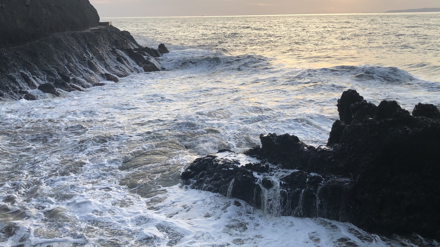 Escena costera con olas rompiendo contra las rocas