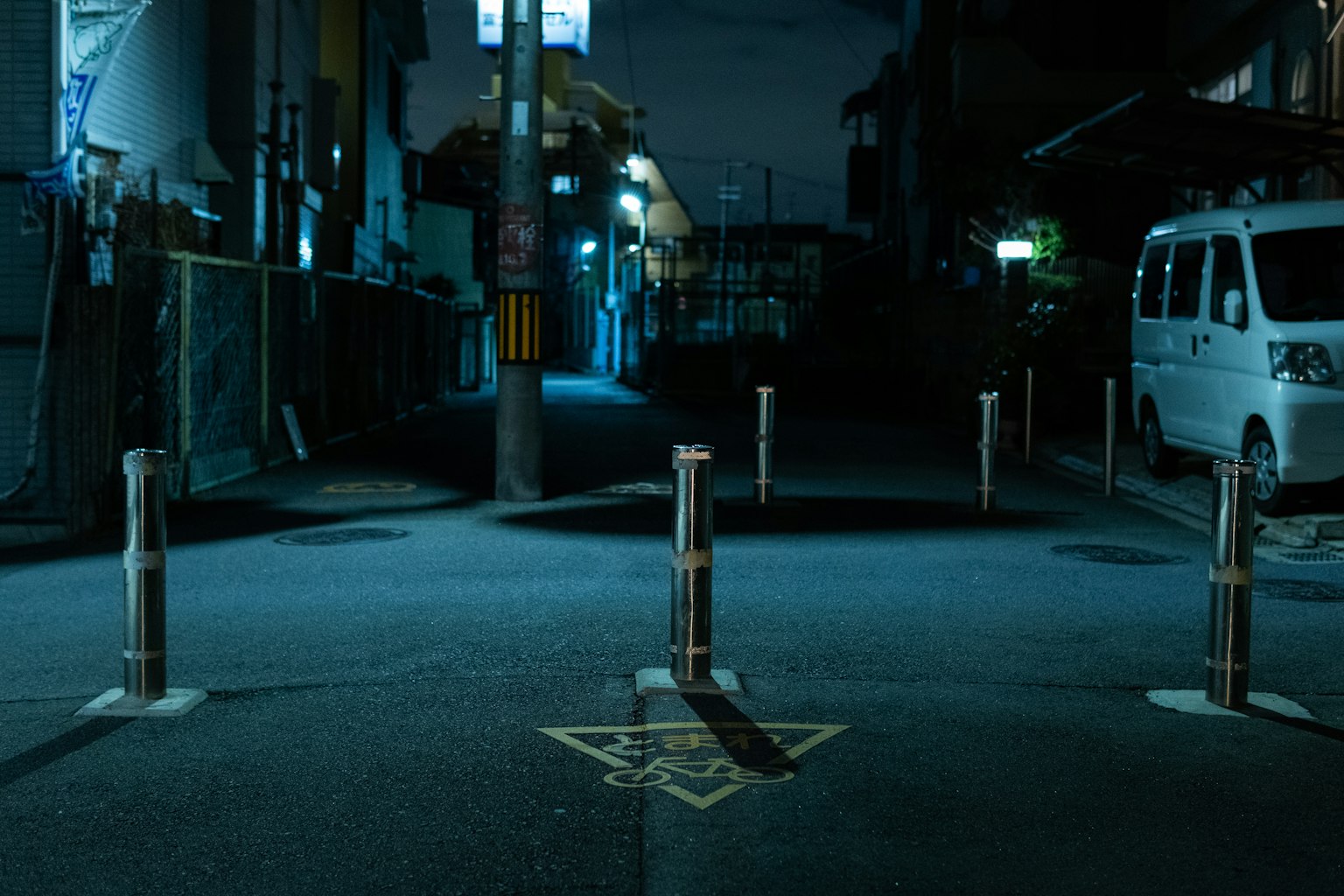 黑暗街道場景，白色車輛和排成一排的交通柱