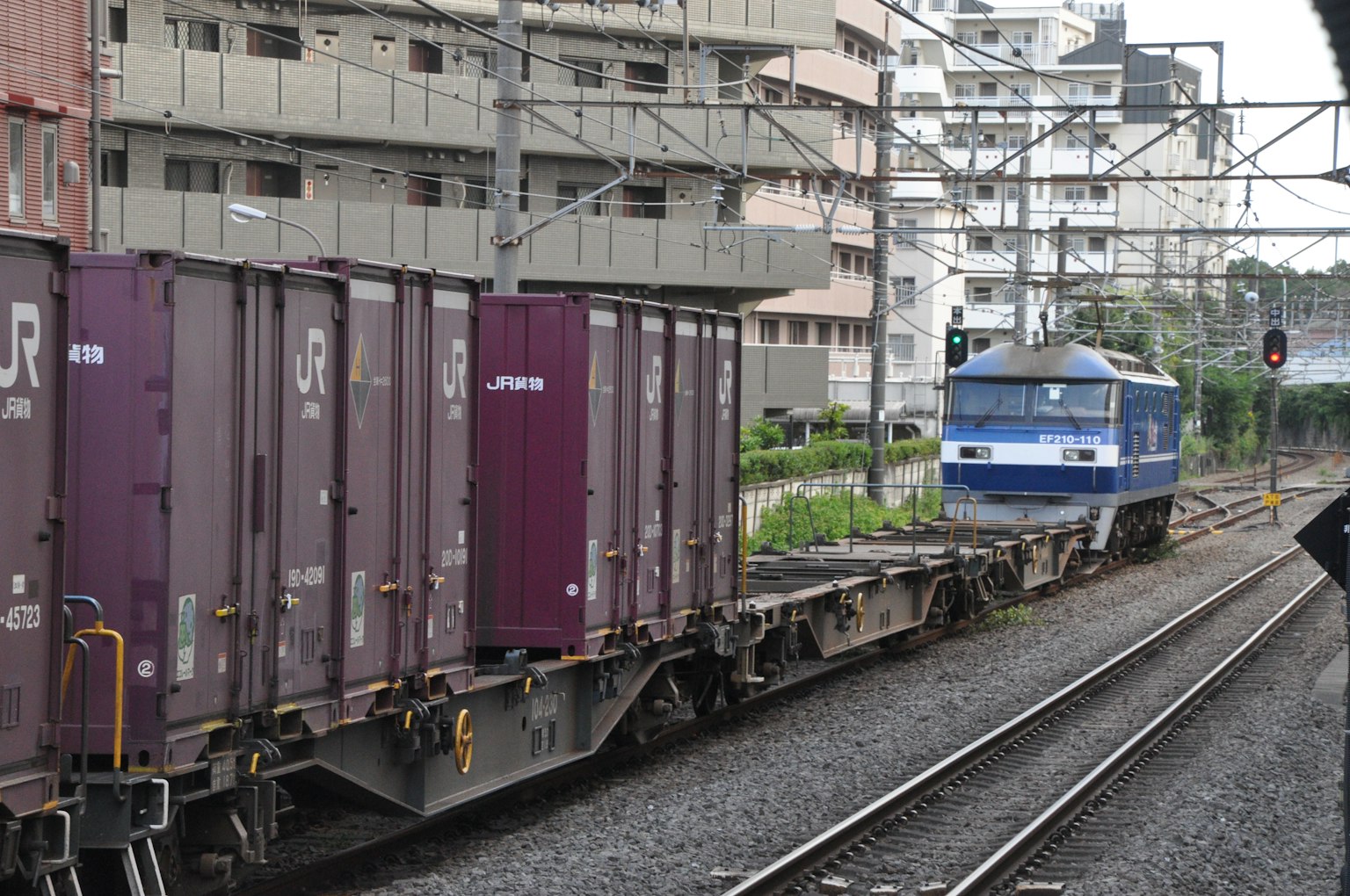 Kereta dengan kontainer kargo ungu dan lokomotif biru di rel