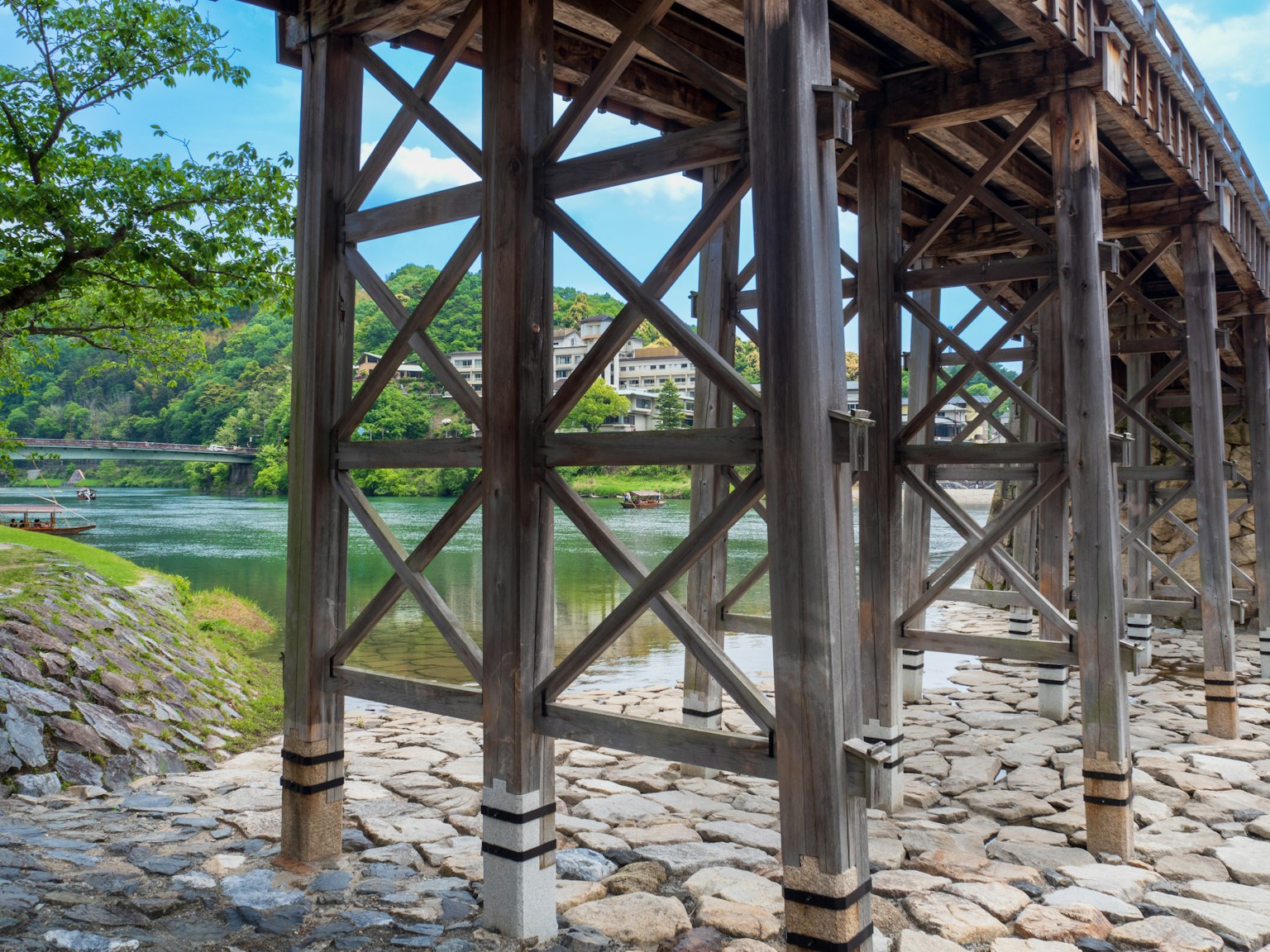 Holzstützen einer Brücke über einem Fluss mit Steinschüttung