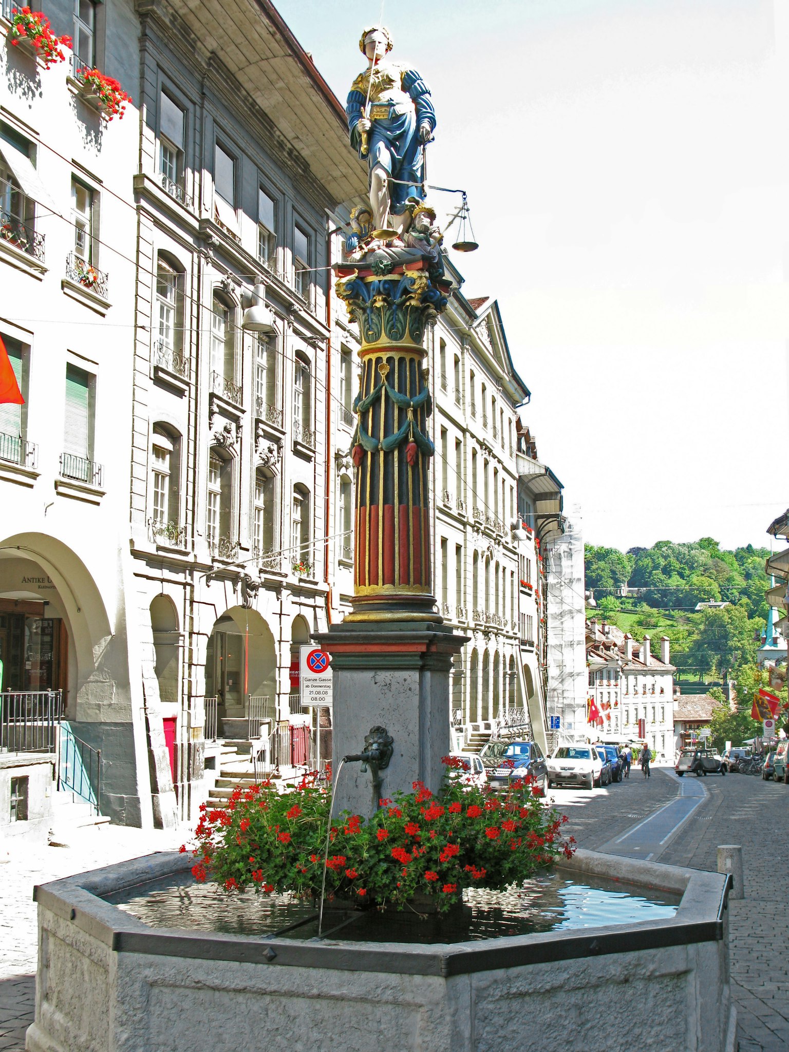 Straßenansicht mit einem bunten Brunnen und lebhaften Blumen