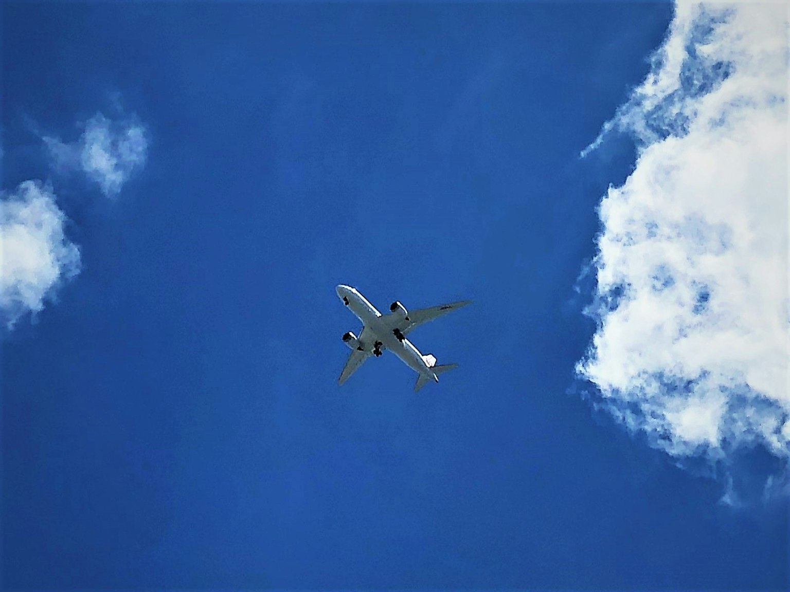 Flugzeug fliegt in einem klaren blauen Himmel mit weißen Wolken