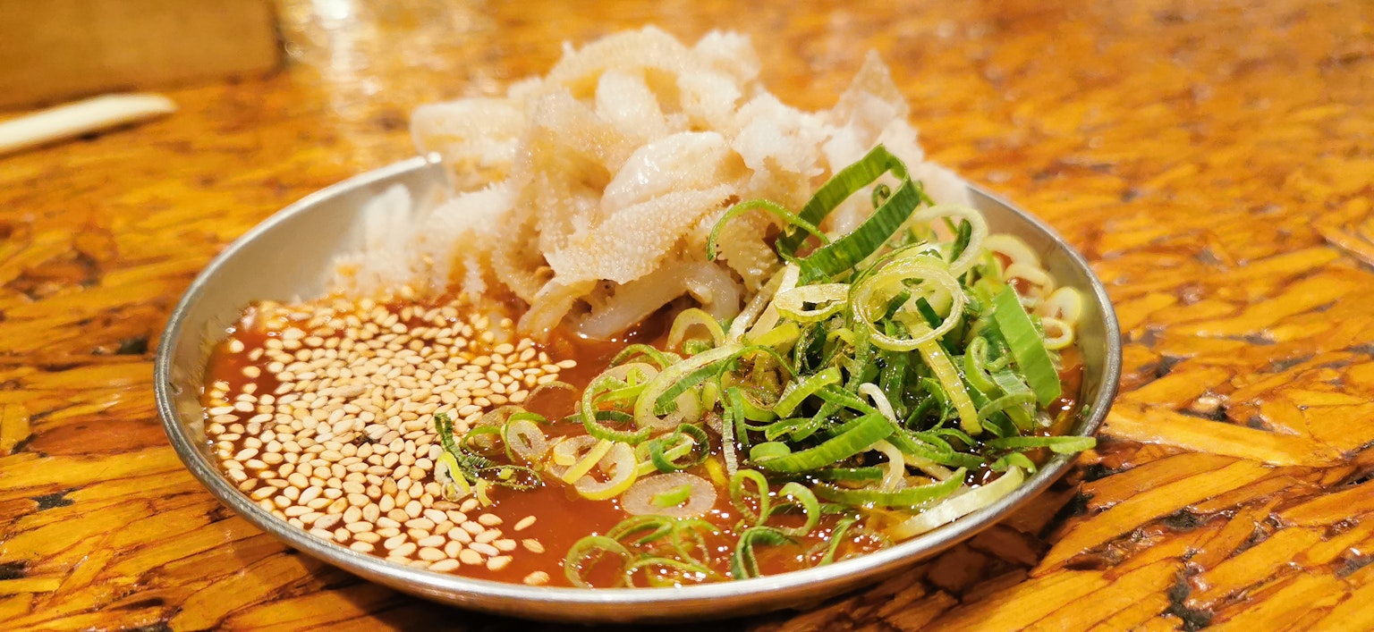 Một đĩa sashimi với cá thái lát hành xanh và hạt mè