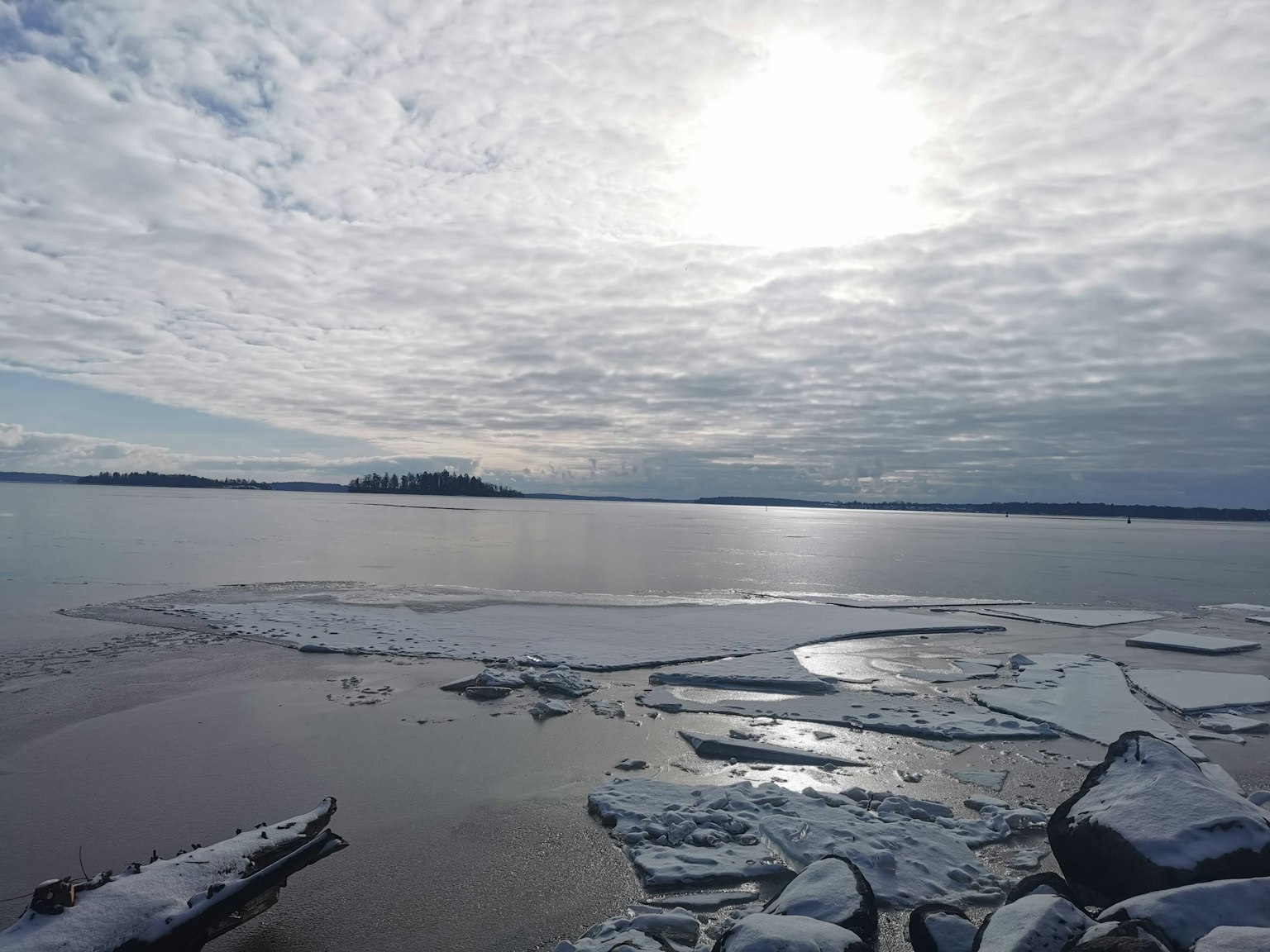 Une vue paisible du lac avec des morceaux de glace flottants sous un ciel nuageux
