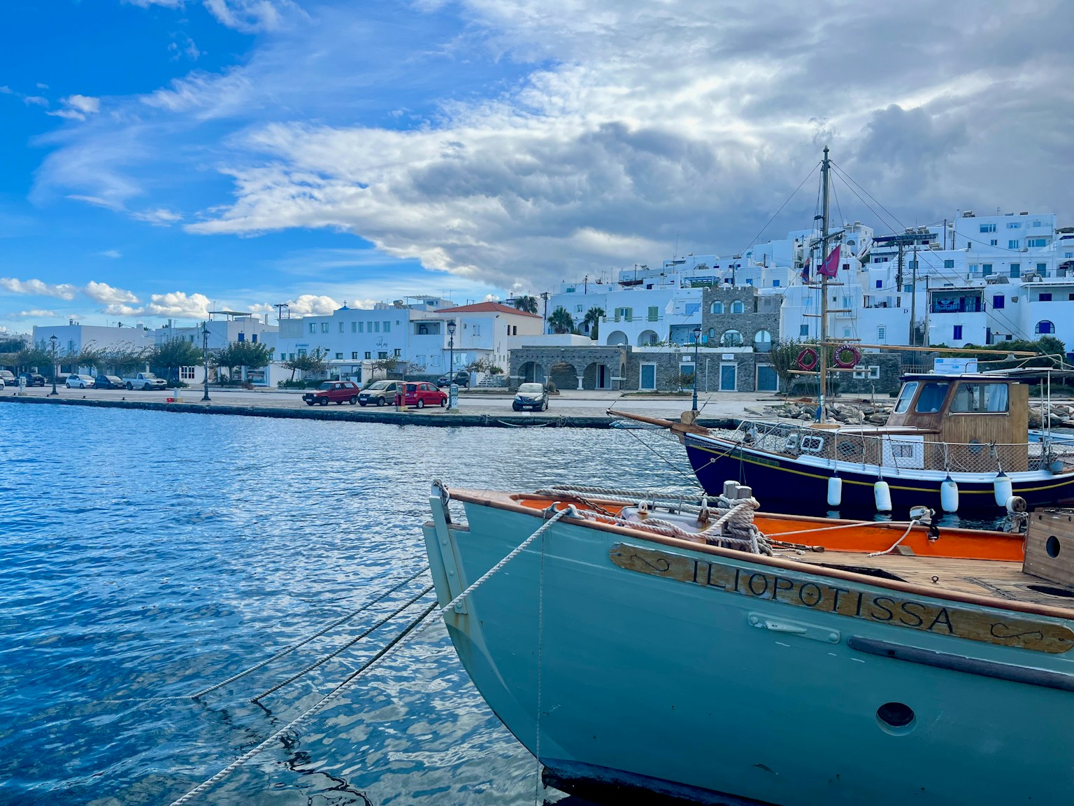 Un bote amarrado en un puerto con agua azul y edificios blancos