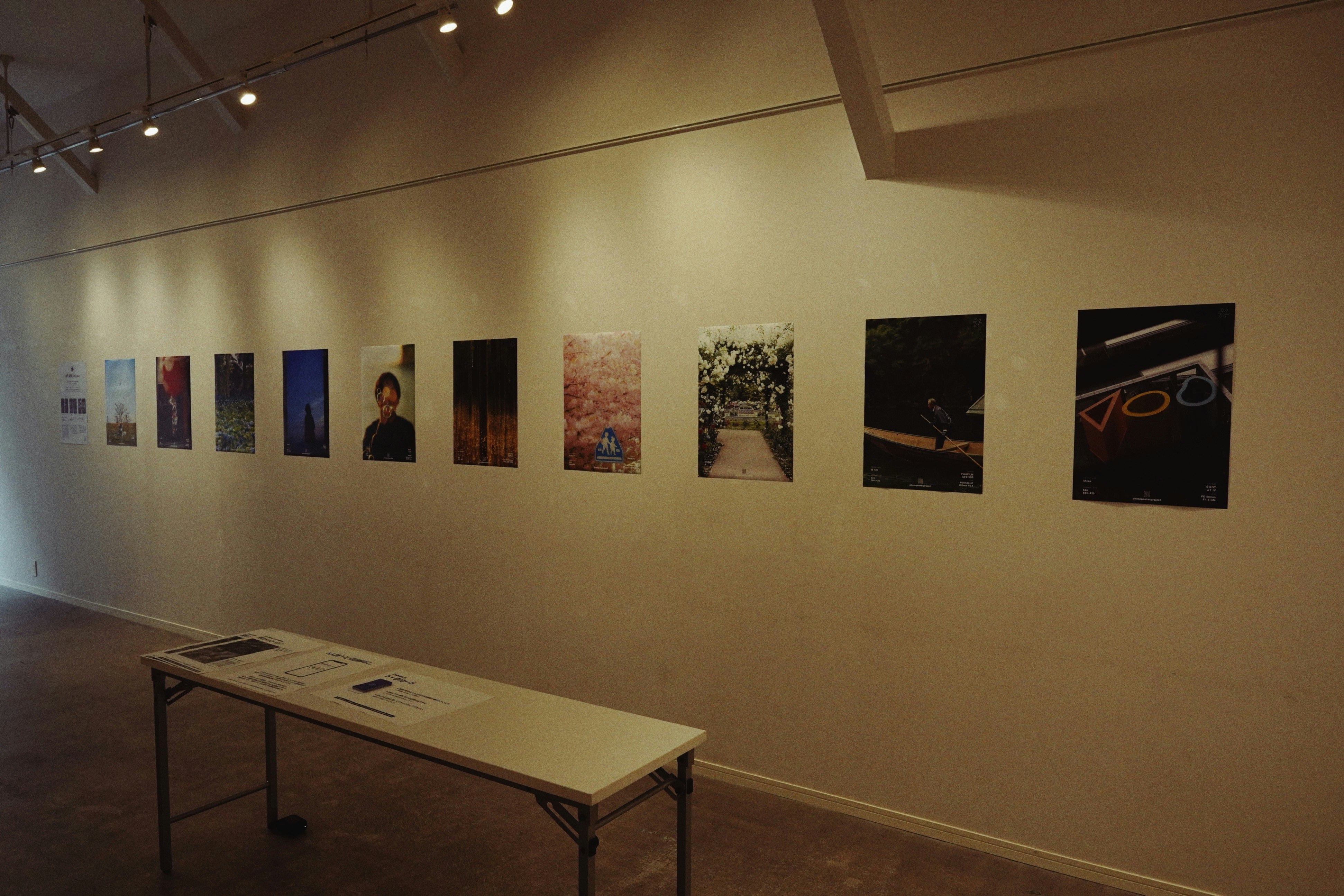 phòng trưng bày trong một gallery ở Kyoto với dãy poster trên tường và bàn trưng bày
